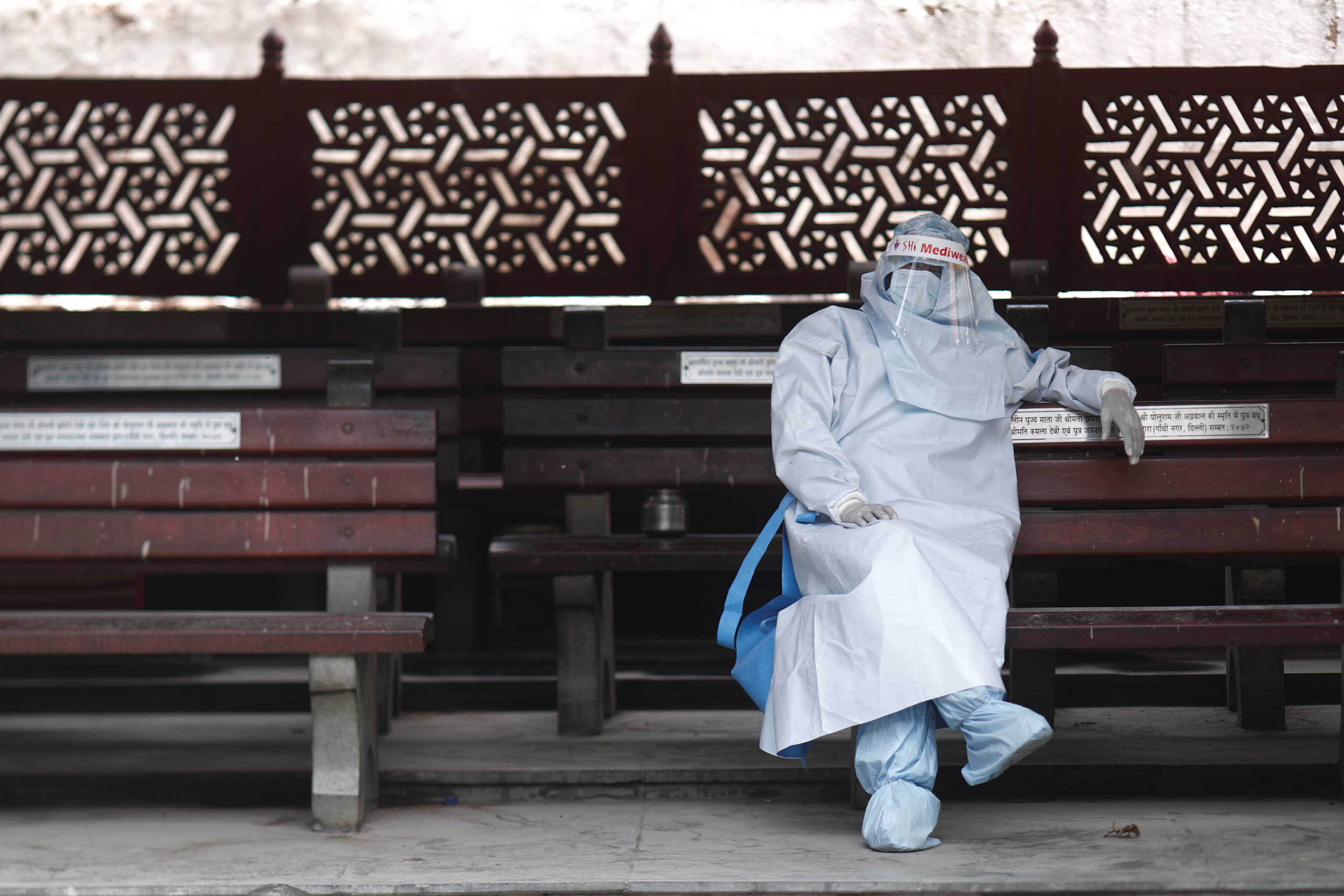A health worker in personal protective equipment (PPE) rests before the cremation of a man who died due to the coronavirus disease (COVID-19), at a crematorium in New Delhi, India July 5, 2020. REUTERS