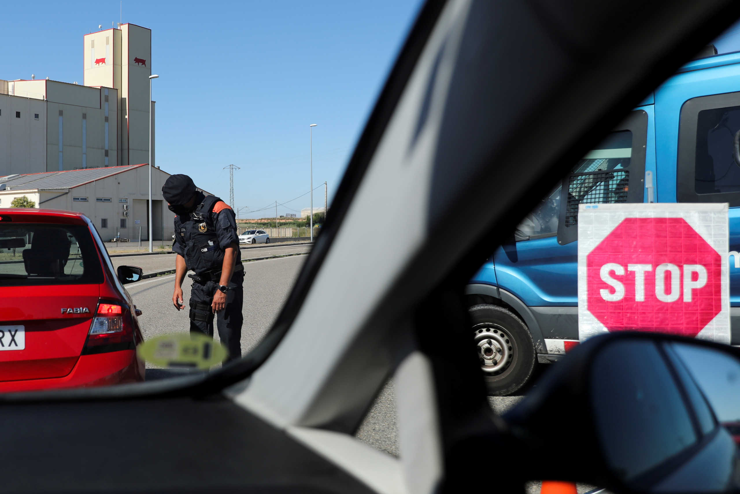 FILE PHOTO: A Police officer checks the documents of people travelling on vehicles at the entrance of Lleida after Catalonia's government imposed new restrictions to control a new coronavirus disease (COVID-19) outbreak in Lleida, Spain, July 4, 2020. REUTERS