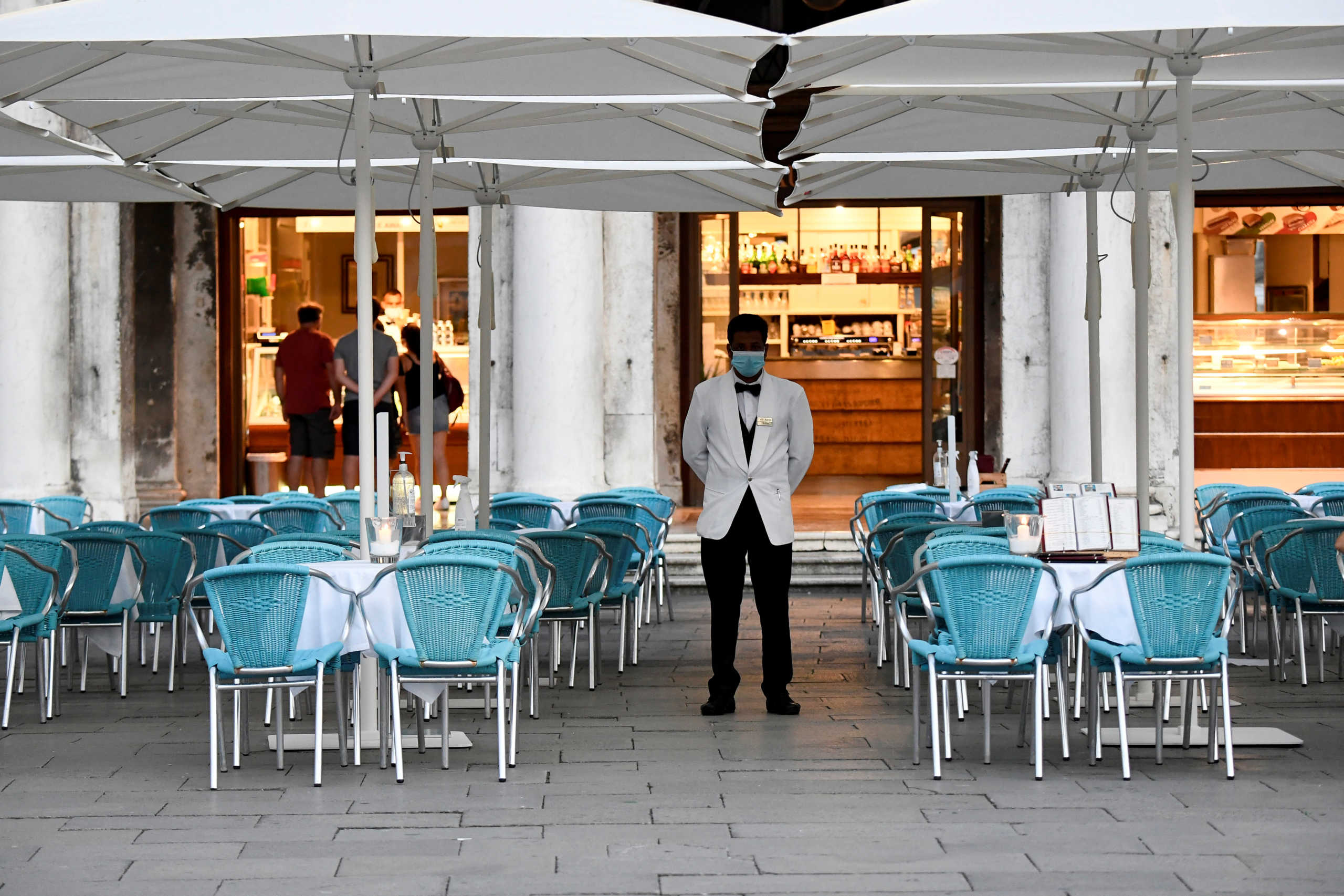 A bar employee wears a protective face mask while standing at St. Mark's Square amid the coronavirus disease (COVID-19) outbreak in Venice, Italy  July 9, 2020. REUTERS