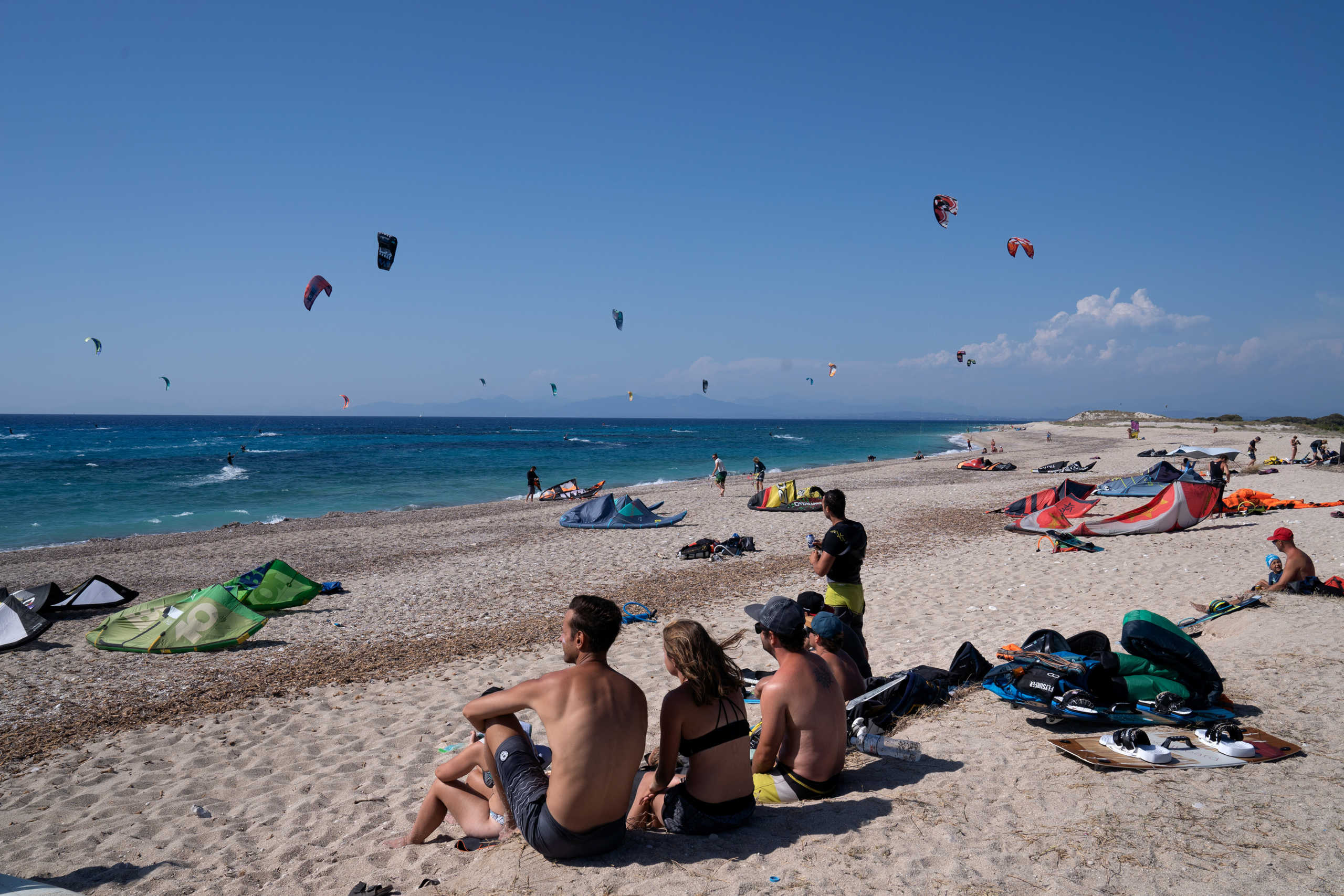 People watch kitesurfers at Mylos beach, following the easing of measures against the spread of the coronavirus disease (COVID-19), on the island of Lefkada, Greece, July 25, 2020. Picture taken July 25, 2020. REUTERS