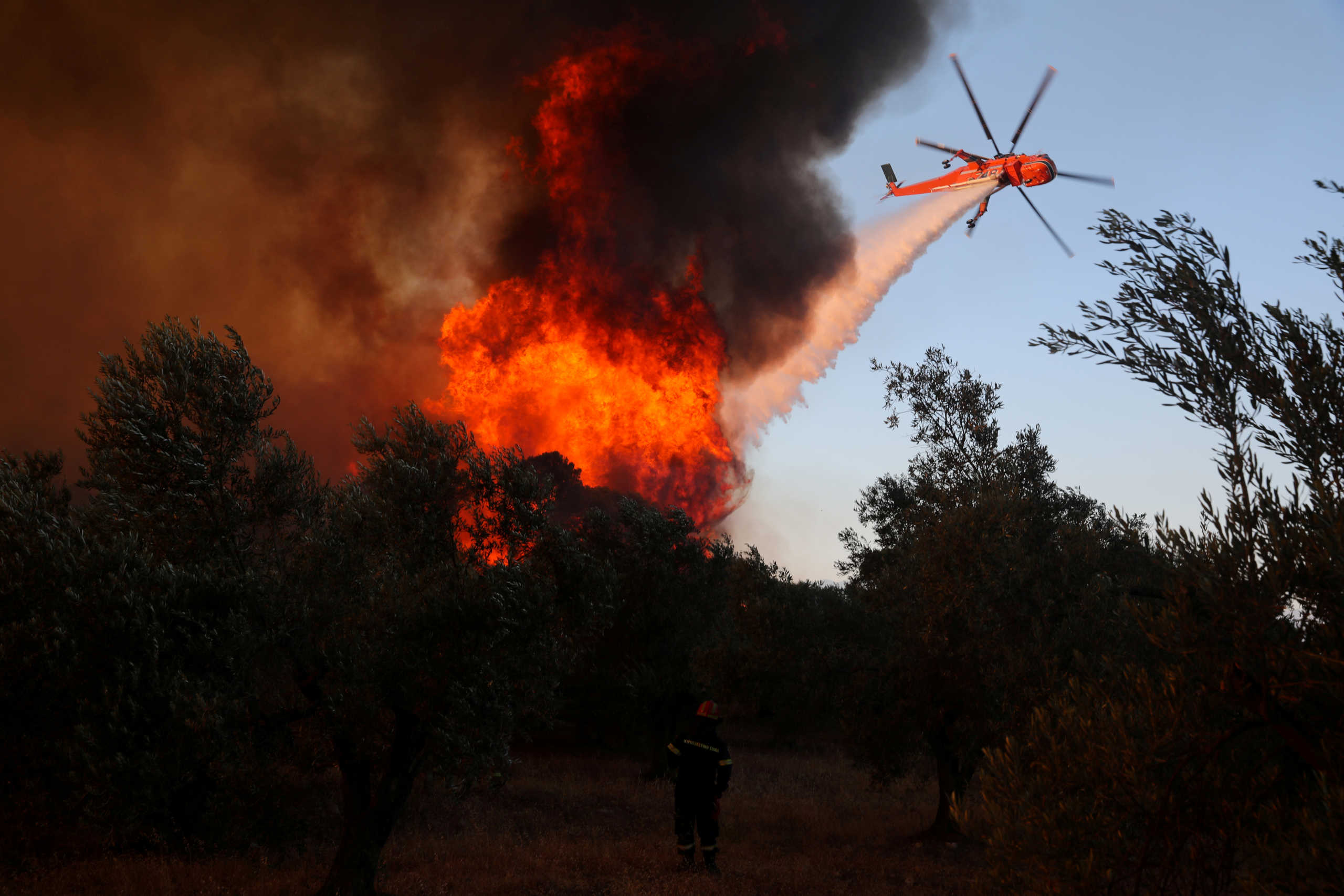 A helicopter makes a water drop as a wildfire burns near the village of Kechries, Greece, July 22, 2020. REUTERS