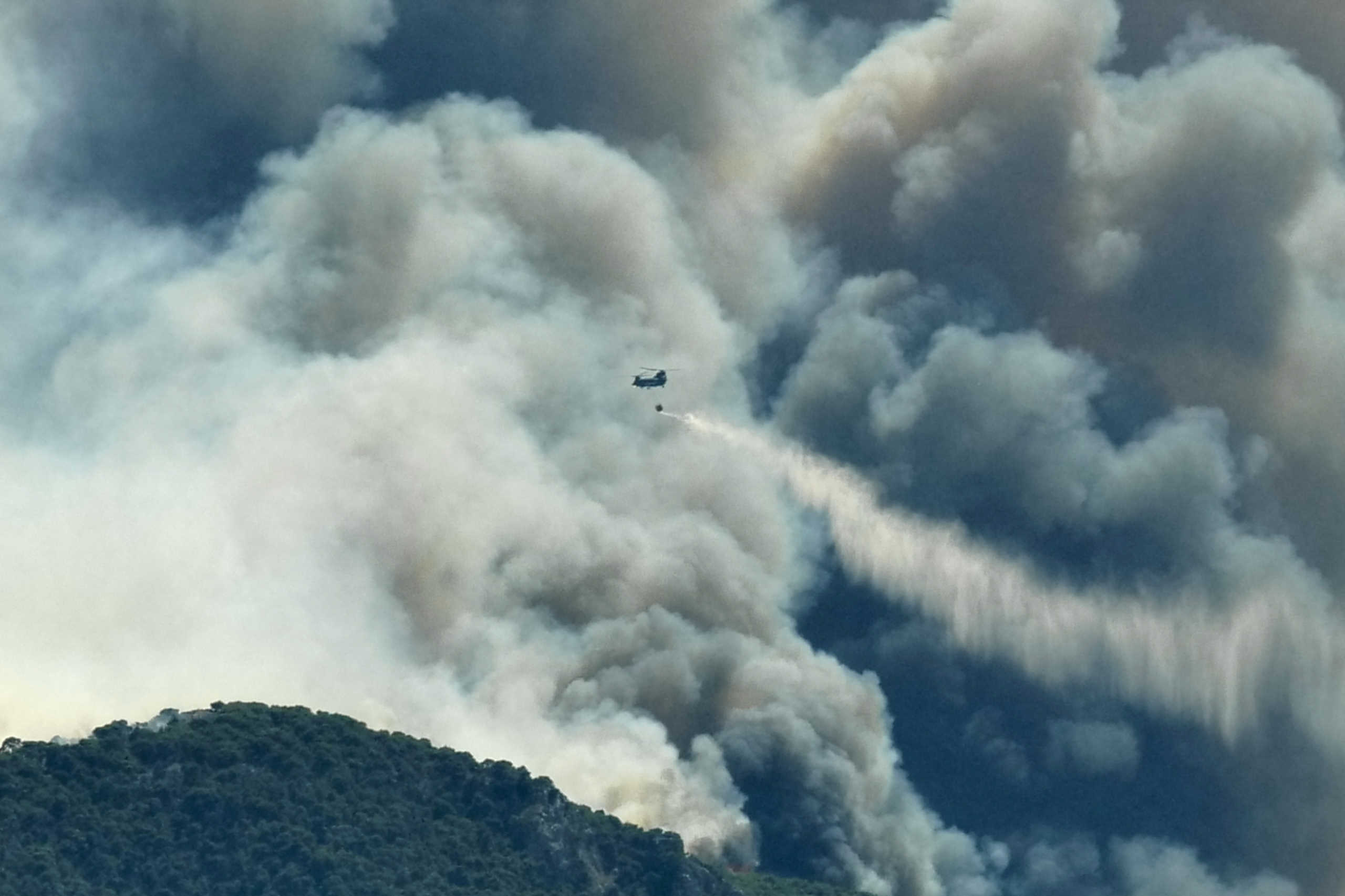 A Chinook helicopter makes a water drop as a wildfire burns near the village of Kechries, Greece, July 22, 2020. REUTERS