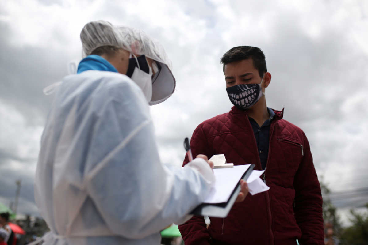 An employee of the Ministry of Health wearing protective gear talks to a man wearing a face mask who will undergo a rapid test for the coronavirus disease (COVID-19), in Bogota, Colombia July 1, 2020. REUTERS