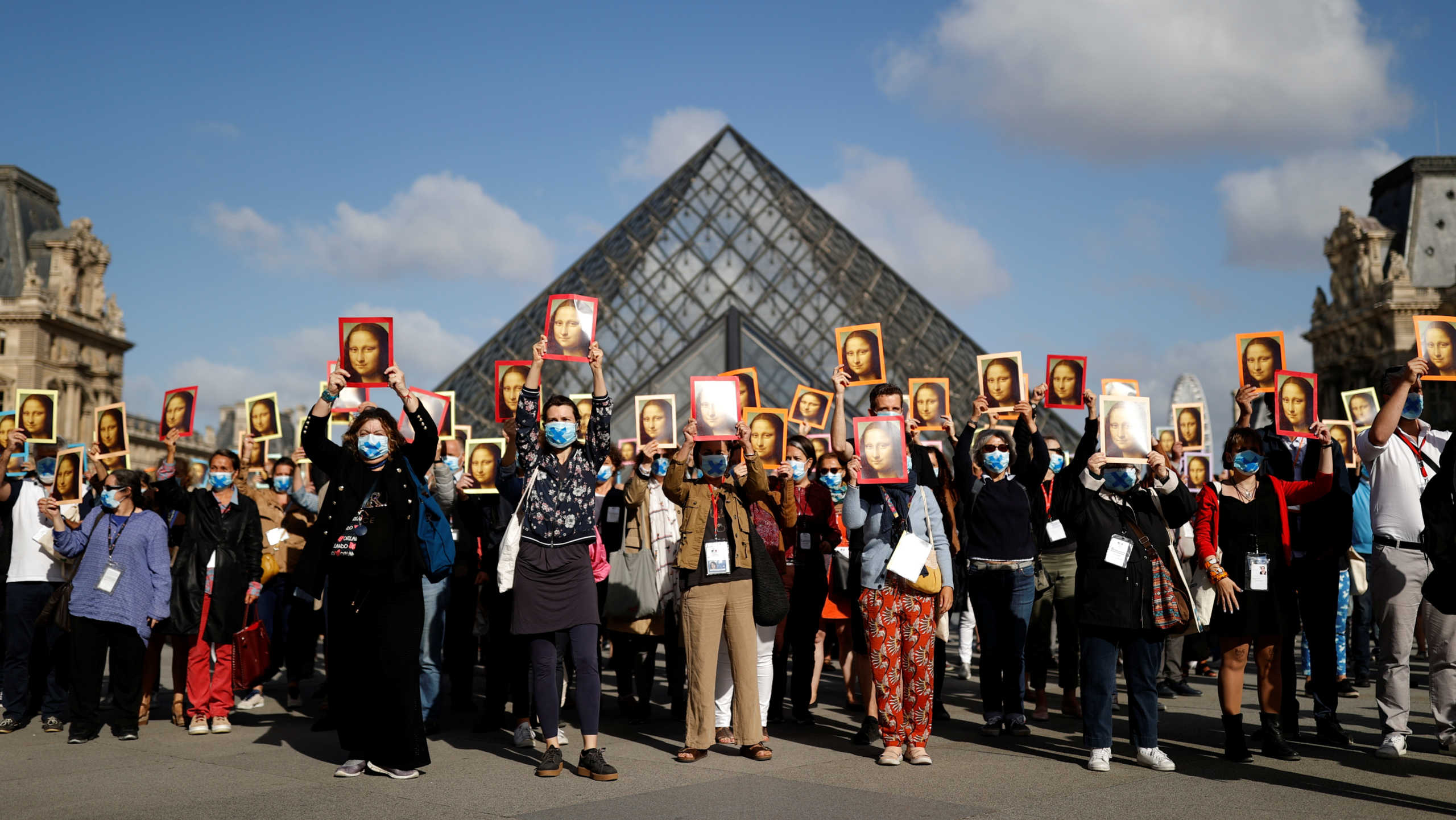 Paris tour guides hold posters depicting Mona Lisa painting by artist Leonardo da Vinci during an action at Le Louvre museum courtyard to warn on their working conditions as the museum reopens its doors to the public after almost 4-month closure due to the coronavirus disease (COVID-19) outbreak in France, July 6, 2020. REUTERS