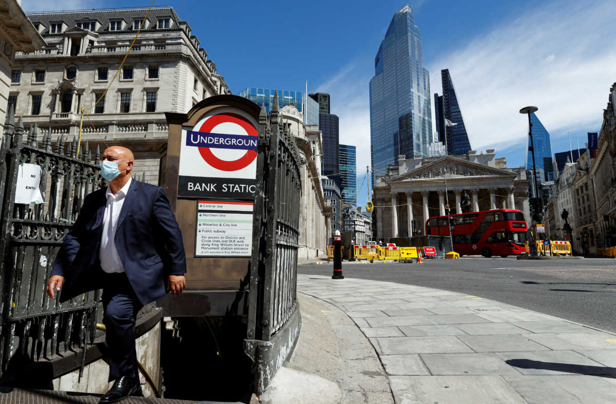 A man wearing a face mask and suit exits Bank underground station, in front of the Bank of England and Royal Exchange Building, amid the coronavirus disease (COVID-19) outbreak, in London, Britain, July 30, 2020.  REUTERS