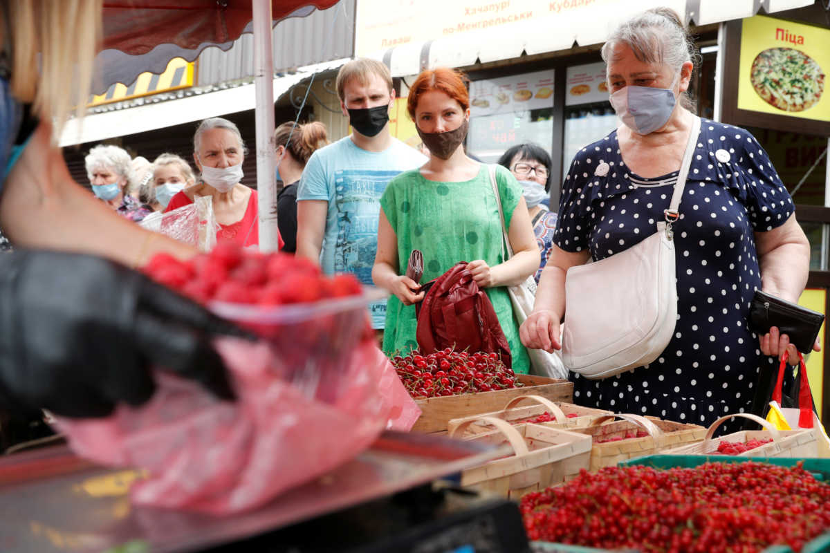People wearing protective face masks stay in queue to buy fruits at a market, amid the outbreak of the coronavirus disease (COVID-19) in Kyiv, Ukraine July 7, 2020.  REUTERS