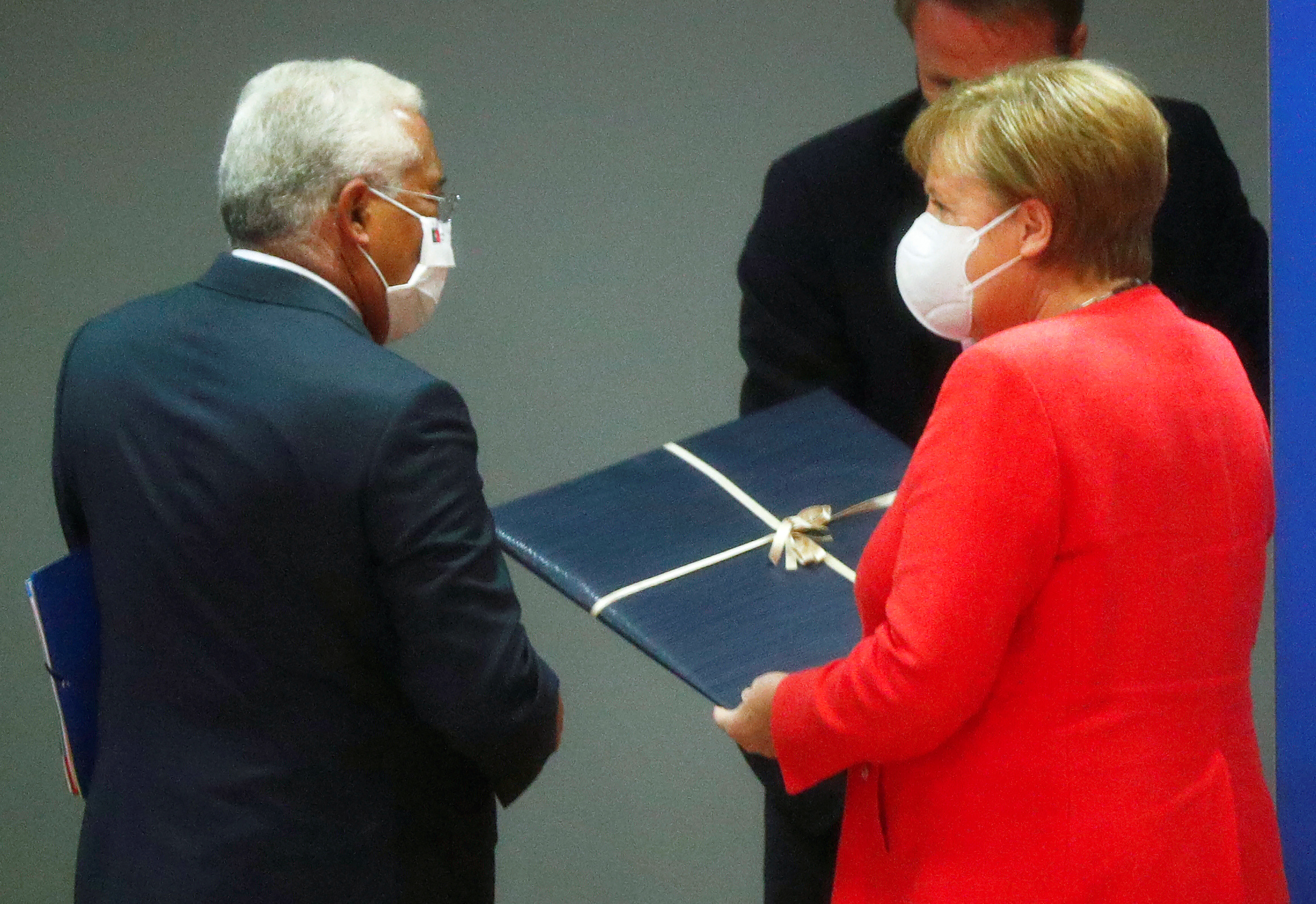 Portugal's Prime Minister Antonio Costa gives a birthday present to German Chancellor Angela Merkel during the first face-to-face EU summit since the coronavirus disease (COVID-19) outbreak, in Brussels, Belgium July 17, 2020. REUTERS