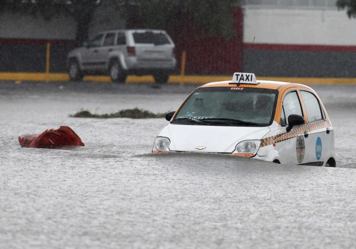 A taxi driver is seen crossing a flooded street during the Storm Hanna in Apodaca on the outskirts of Monterrey, Mexico July 26, 2020. REUTERS