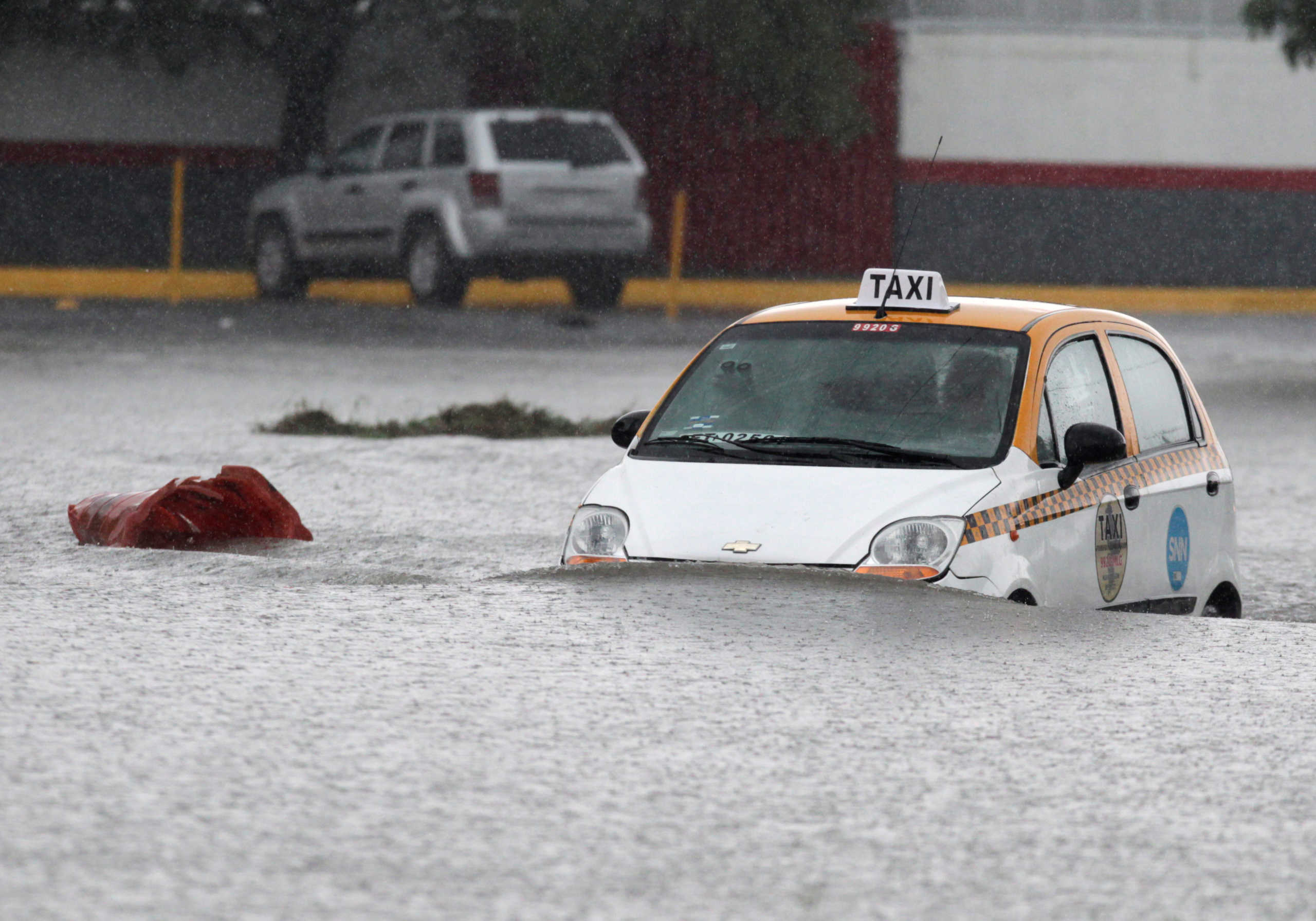 A taxi driver is seen crossing a flooded street during the Storm Hanna in Apodaca on the outskirts of Monterrey, Mexico July 26, 2020. REUTERS