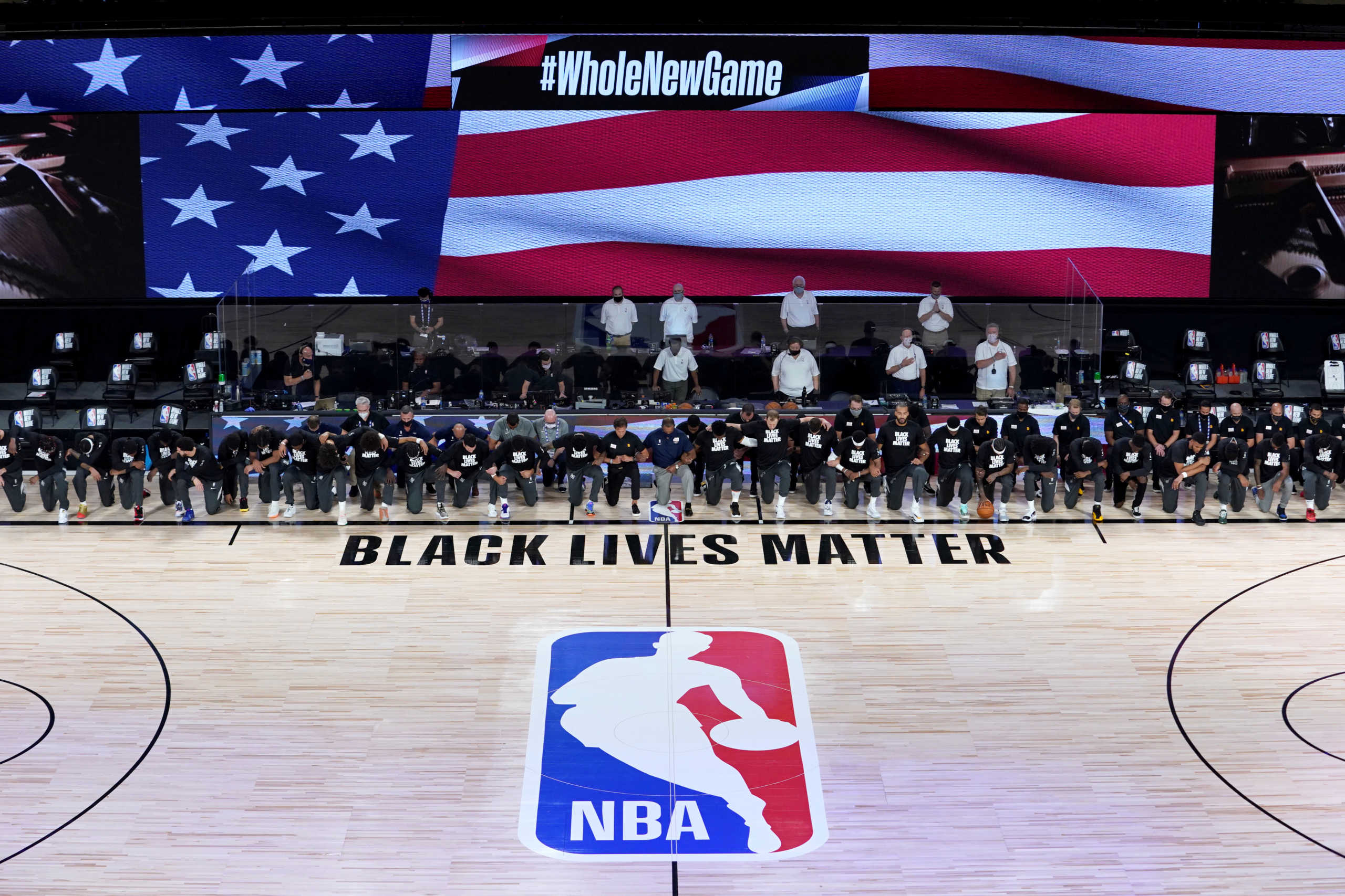 July 30, 2020; Lake Buena Vista, USA; Members of the New Orleans Pelicans and Utah Jazz kneel together around the Black Lives Matter logo on the court during the national anthem before the start of an NBA basketball game.  Mandatory Credit: Ashley Landis