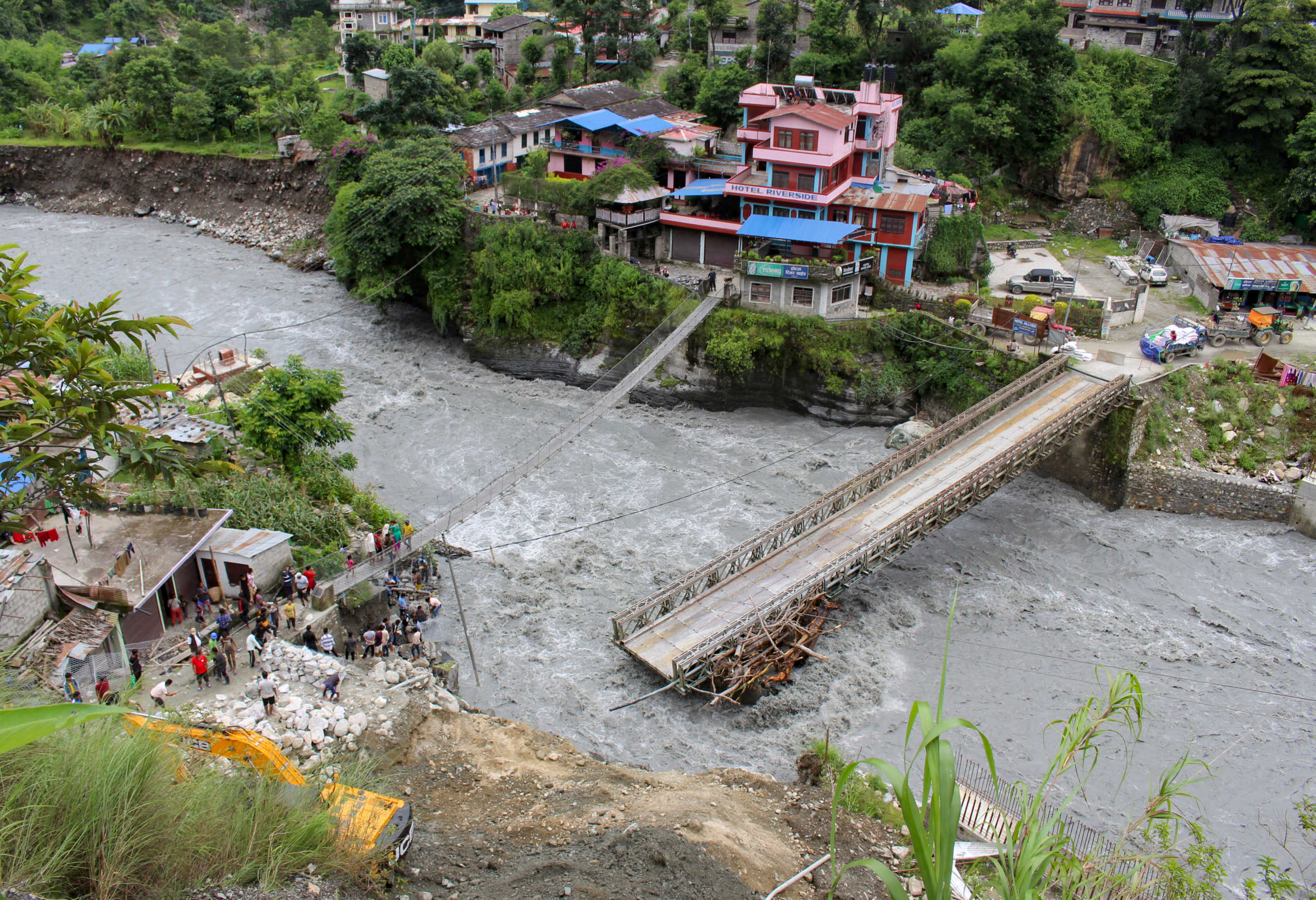 People gather near the bridge that is damaged due to the flood at Raghu Ganga River in Myagdi, Nepal July 11, 2020. REUTERS