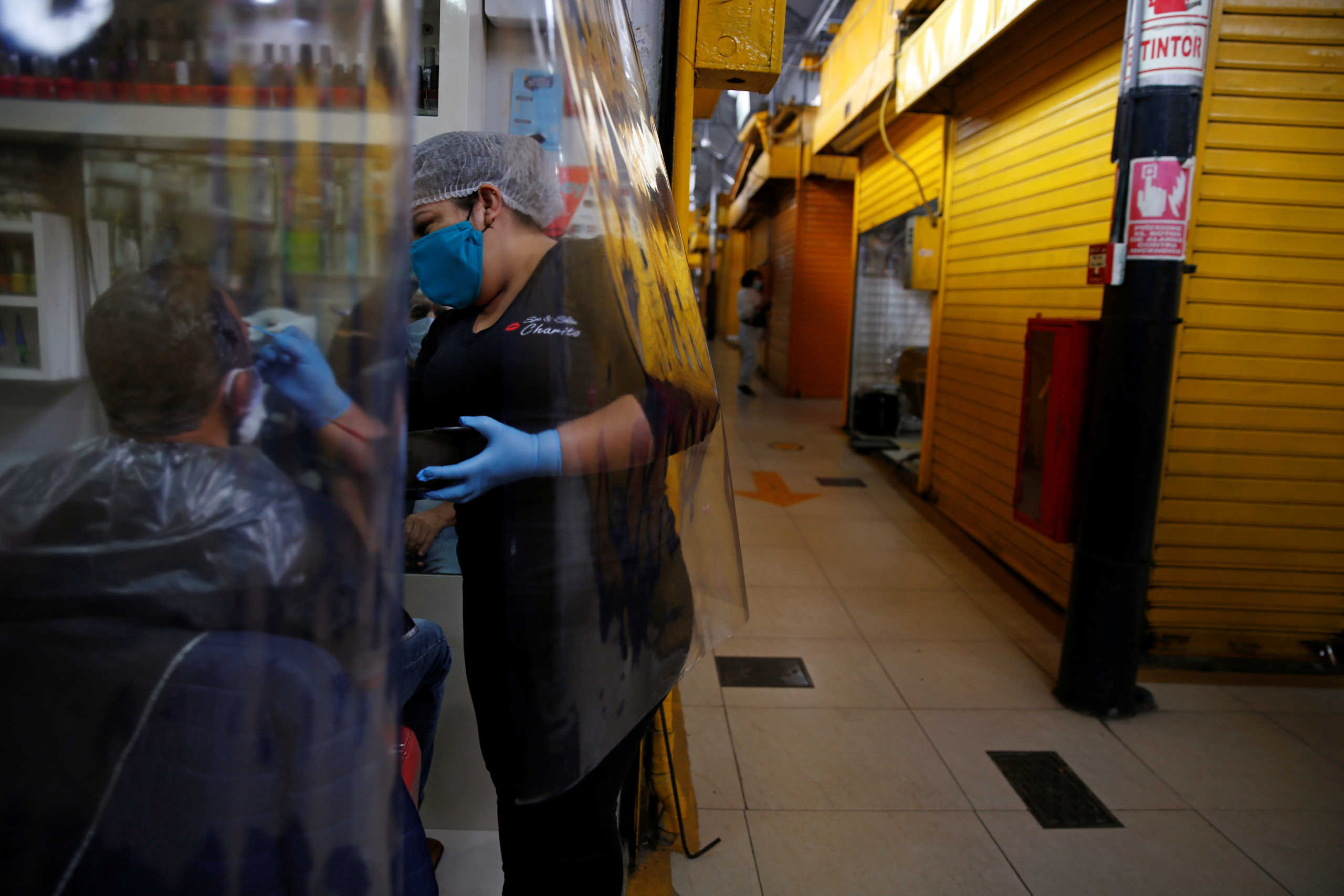 A hairdresser attends to a client as businesses reopen after the end of months-long lockdown, to try and contain the spread of the coronavirus disease (COVID-19), in Lima, Peru July 2, 2020. REUTERS