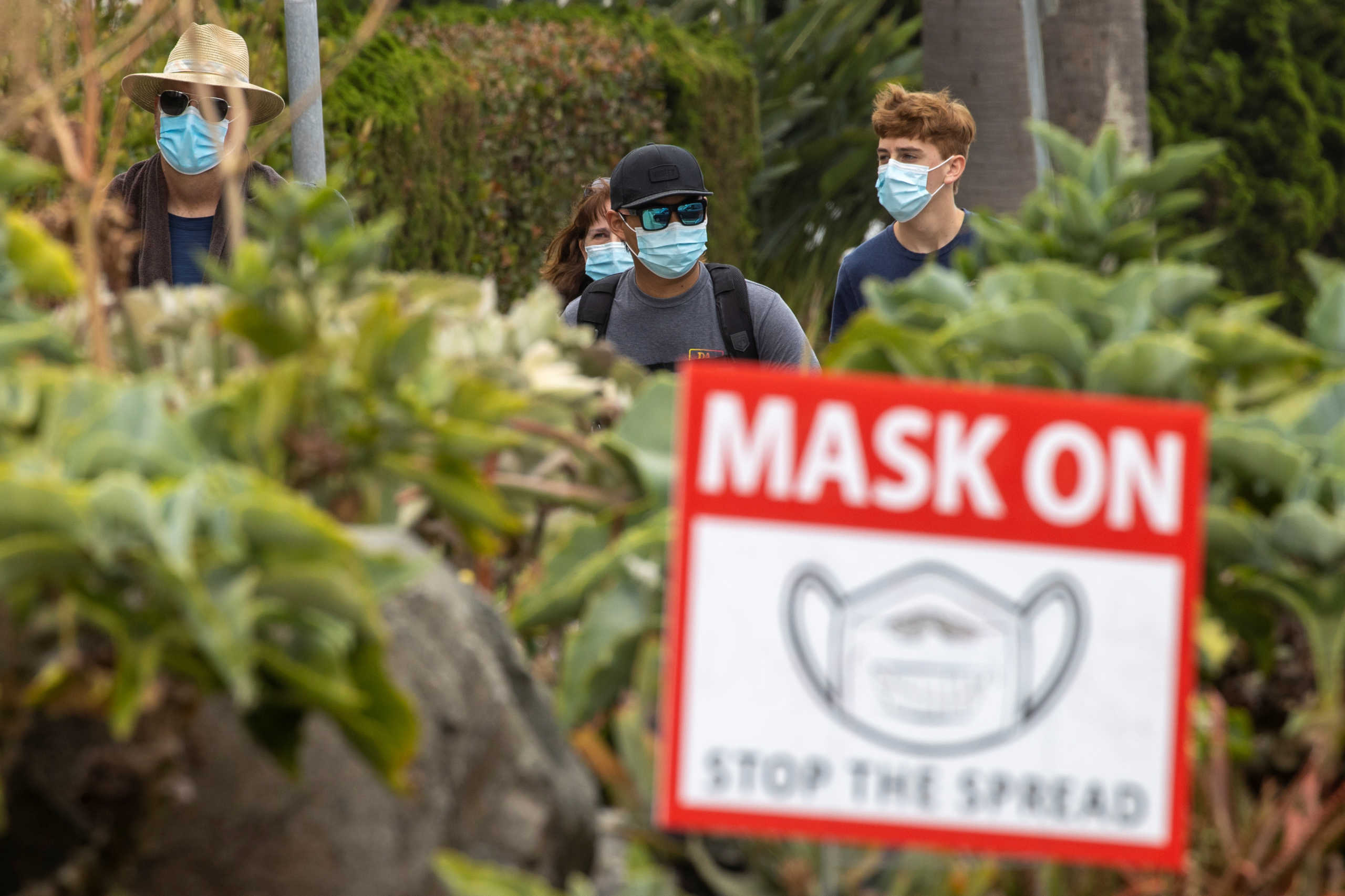 People wear masks as they walk along the side walk during the outbreak of the coronavirus disease (COVID-19) in Del Mar, California, U.S., July 30, 2020.      REUTERS
