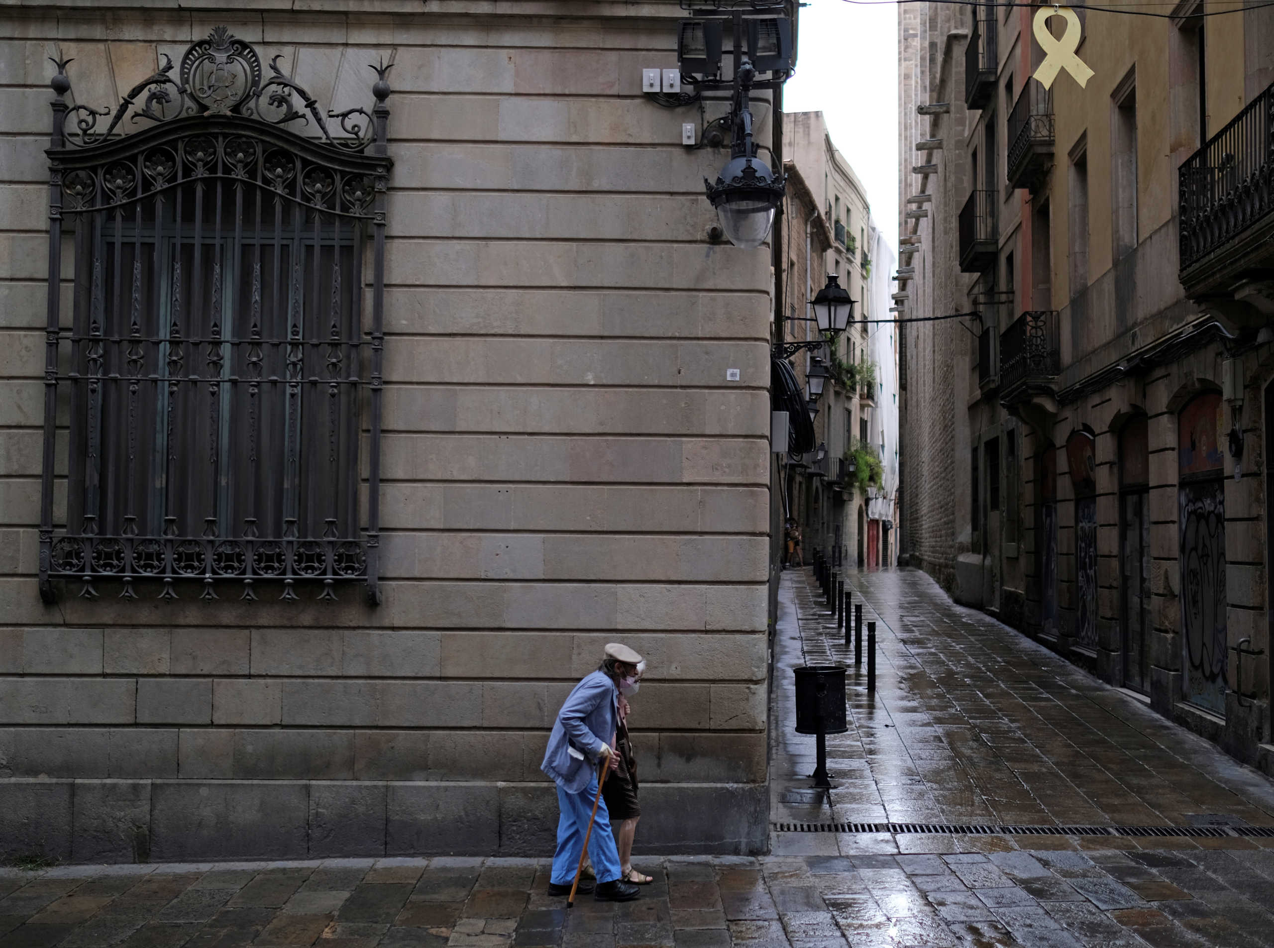 A couple of elderly people wearing face masks walk on a street, after Catalonia's regional authorities and the city council announced restrictions to contain the spread of the coronavirus disease (COVID-19) in Barcelona, Spain July 17, 2020. REUTERS