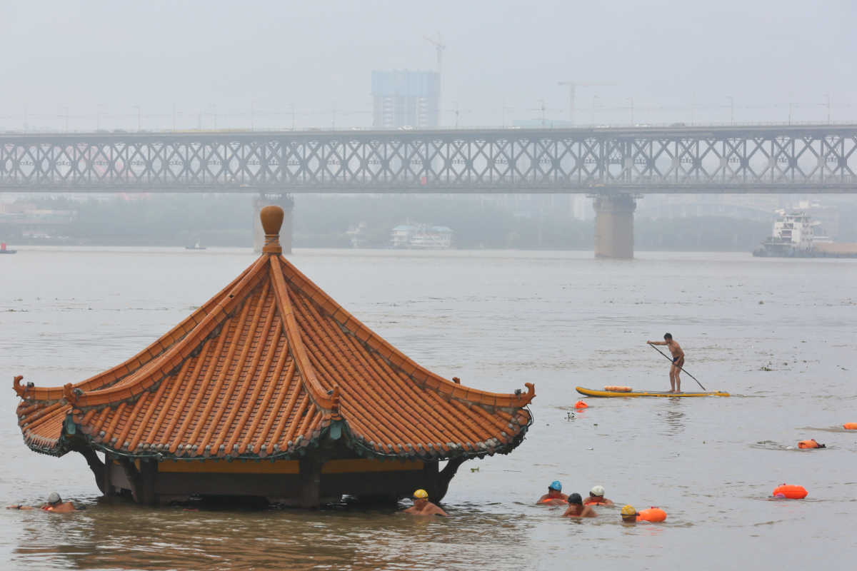 People swim near a pavilion partially submerged in floodwaters on the banks of the Yangtze River, following heavy rainfall in Wuhan, Hubei province, China July 8, 2020. China Daily via REUTERS  ATTENTION EDITORS - THIS IMAGE WAS PROVIDED BY A THIRD PARTY. CHINA OUT.