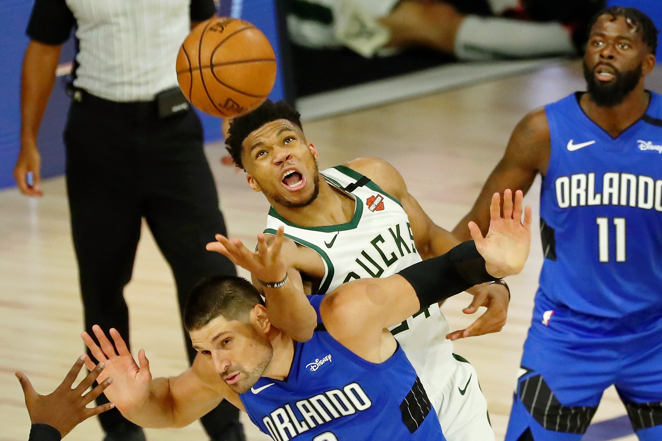 Aug 18, 2020; Lake Buena Vista, Florida, USA; Milwaukee Bucks forward Giannis Antetokounmpo (34) fouls Orlando Magic center Nikola Vucevic (9) while reaching for a loose ball during the second half of Game 1 of an NBA basketball first-round playoff series at The Field House. The Orlando Magic won 122-110. Mandatory Credit: Kim Klement-USA TODAY Sports