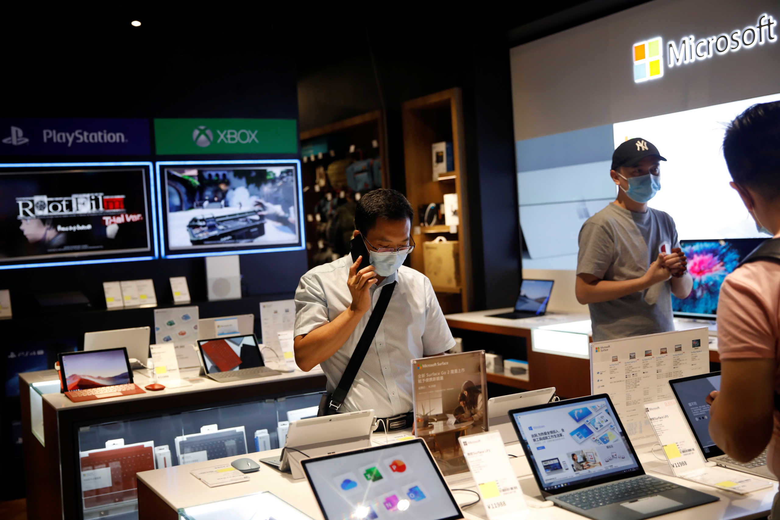 Men wearing face masks look at the merchandise on an electronics store at a shopping mall, following the coronavirus disease (COVID-19) outbreak, in Beijing, China August 3, 2020. REUTERS
