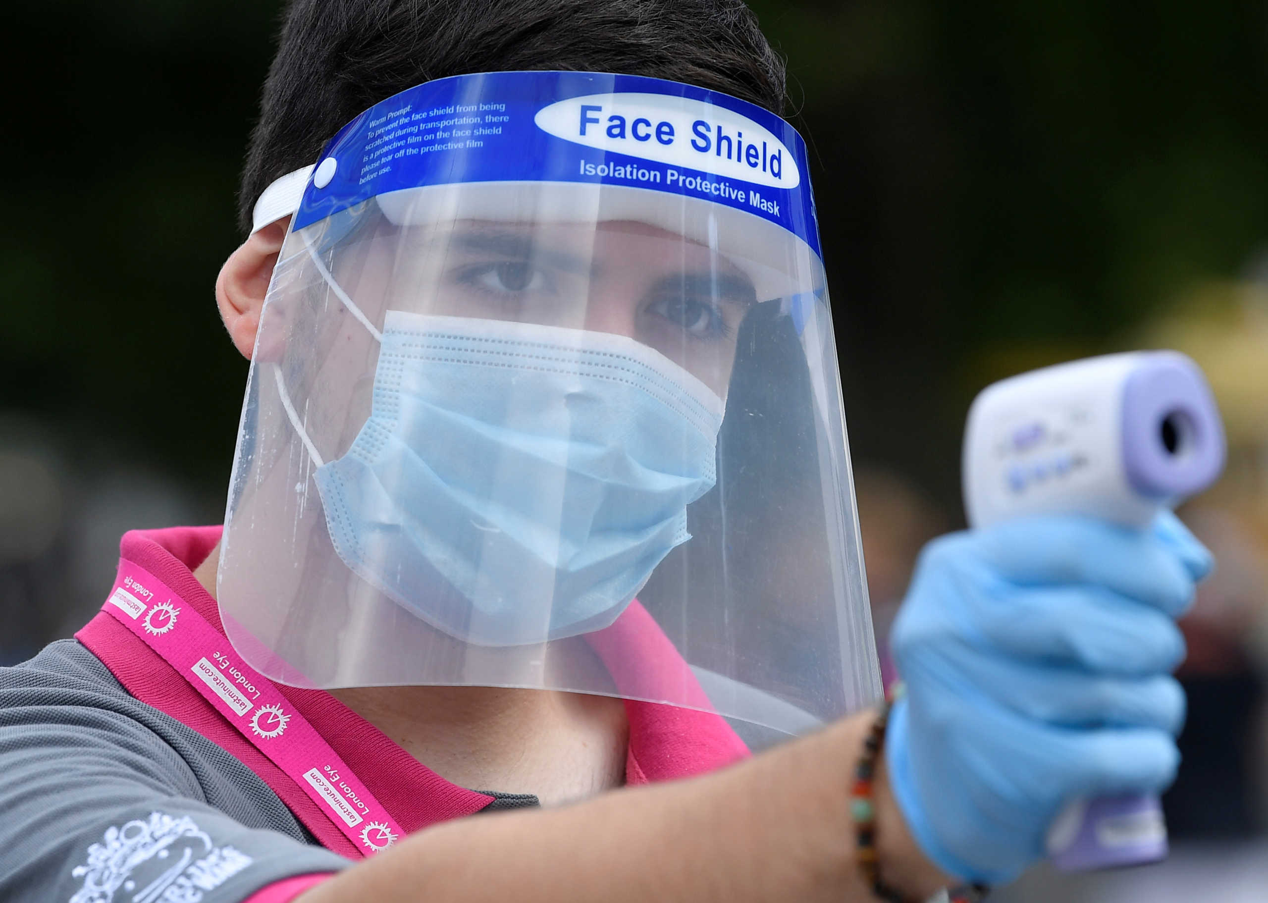 An employee takes the temperature of passengers before they board the London Eye wheel on the first day of its reopening since the easing of lockdown amid the spread of the coronavirus disease (COVID-19), in London, Britain, August 1, 2020. REUTERS