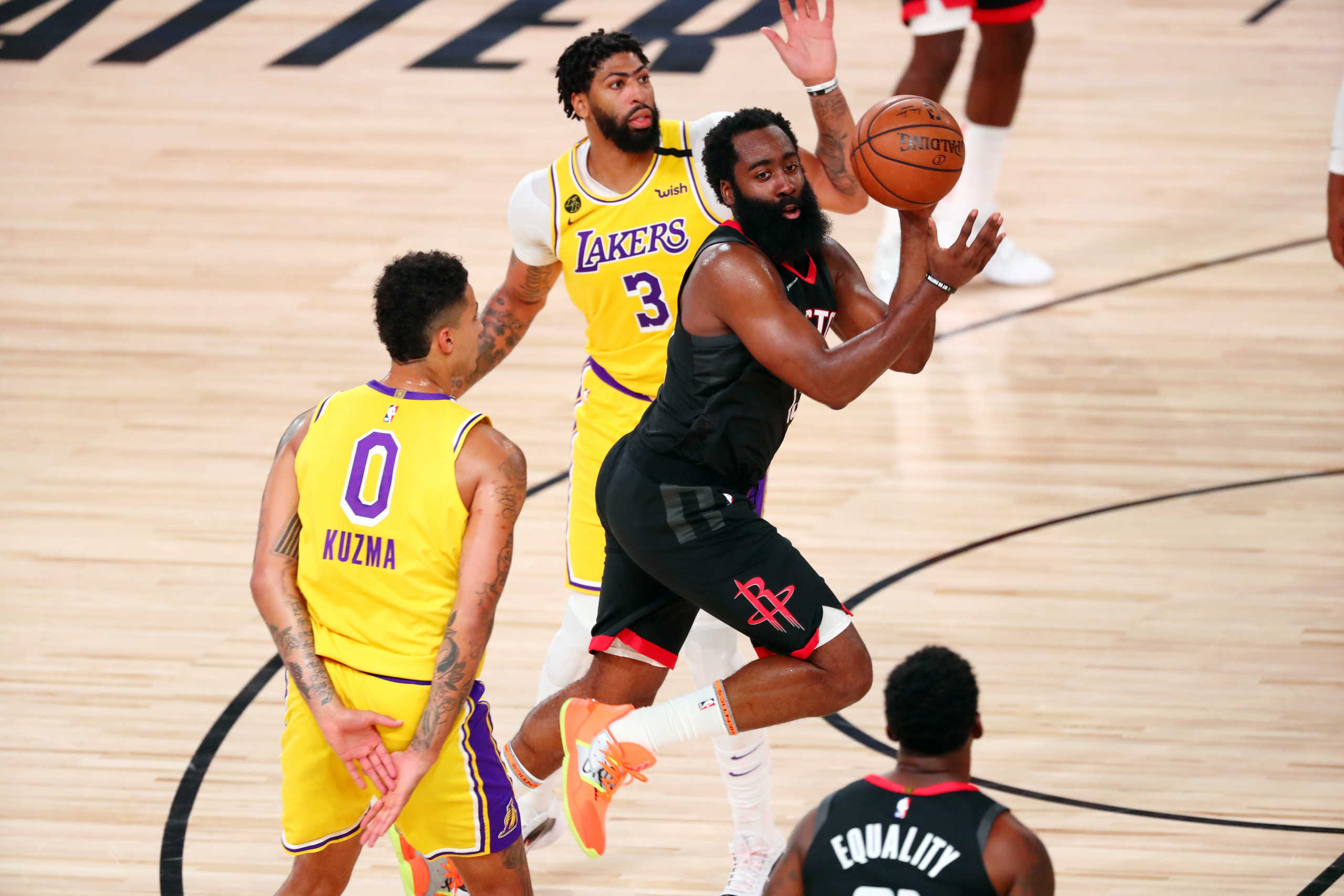 Aug 6, 2020; Lake Buena Vista, Florida, USA; Houston Rockets guard James Harden (13) passes the ball between Los Angeles Lakers forward Kyle Kuzma (0) and forward Anthony Davis (3) during the second half of an NBA basketball game at The Arena. Mandatory Credit: Kim Klement-USA TODAY Sports