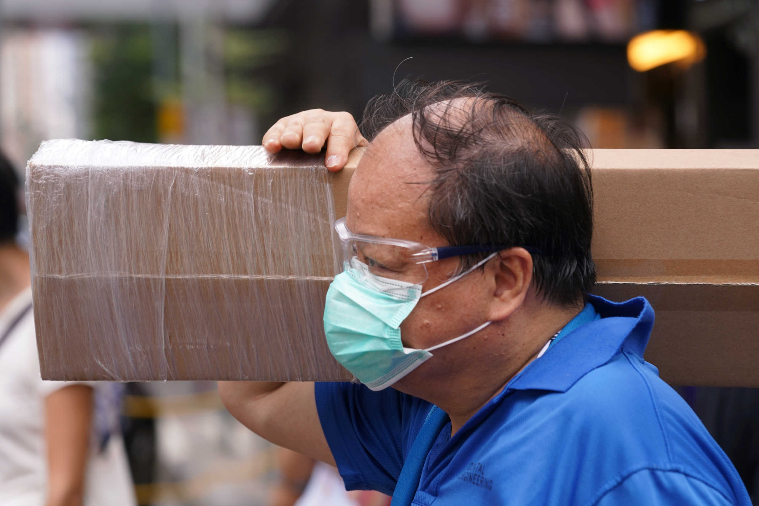 A man wearing a face mask and protective glasses walks on a street following the coronavirus disease (COVID-19) outbreak, in Hong Kong, China August 11, 2020. REUTERS