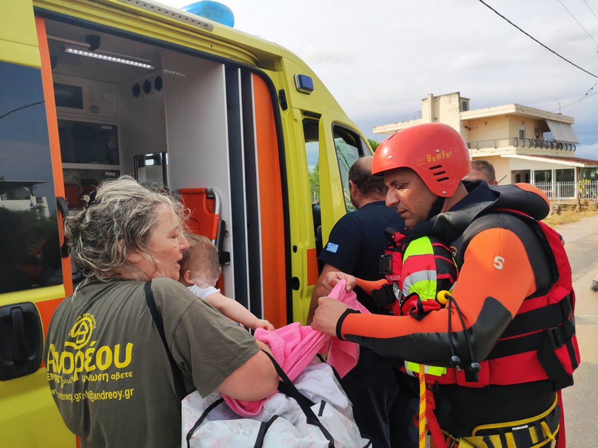 Διασώστης προσφέρει βοήθεια σε μία ηλικιωμένη γυναίκα που κρατάει στα χέρια της ένα μωρό στο Μπούρτζι της Εύβοιας, Κυριακή 09 Αυγούστου 2020, μετά από έντονη κακοκαιρία που έπληξε την περιοχή. Δύο ηλικιωμένοι ανασύρθηκαν νεκροί στα Πολιτικά Ευβοίας από τα σπίτια τους που πλημμύρισαν από την τρομερή νεροποντή που έπνιξε από χτες το βράδυ την περιοχή και ειδικότερα τα Ψαχνά, τα Πολιτικά και το Λευκαντί. Πρόκειται για ένας 86χρονο και μια 85χρονη, οι οποίοι είχαν εγκλωβιστεί στις οικίες τους όπου βρέθηκαν χωρίς τις αισθήσεις τους. ΑΠΕ-ΜΠΕ