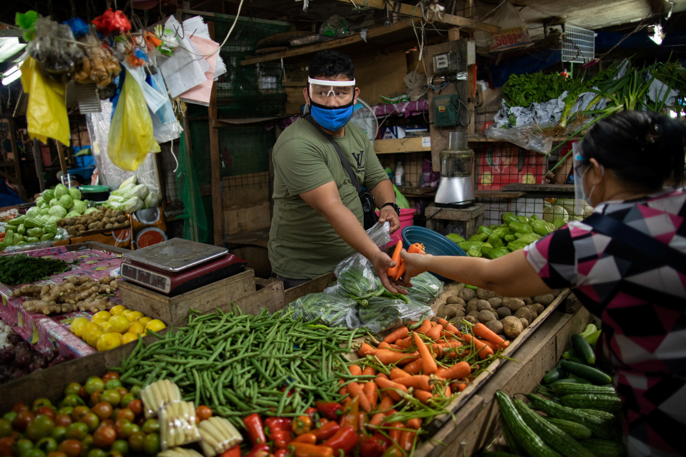 A vendor tends to a customer at a public market where wearing face masks and face shields is mandatory, amid the coronavirus disease (COVID-19) outbreak in Taytay, Rizal province, Philippines, August 11, 2020. REUTERS