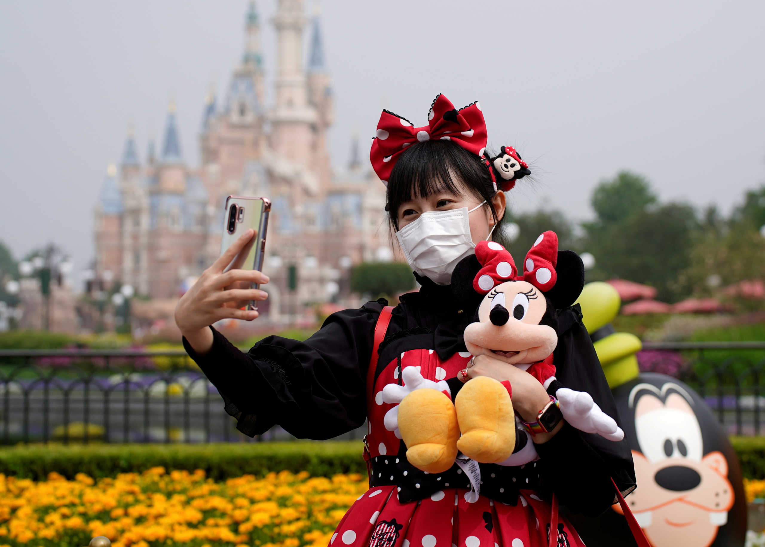 FILE PHOTO: A visitor dressed as a Disney character takes a selfie while wearing a protective face mask at Shanghai Disney Resort as the Shanghai Disneyland theme park in Shanghai, China May 11, 2020. REUTERS