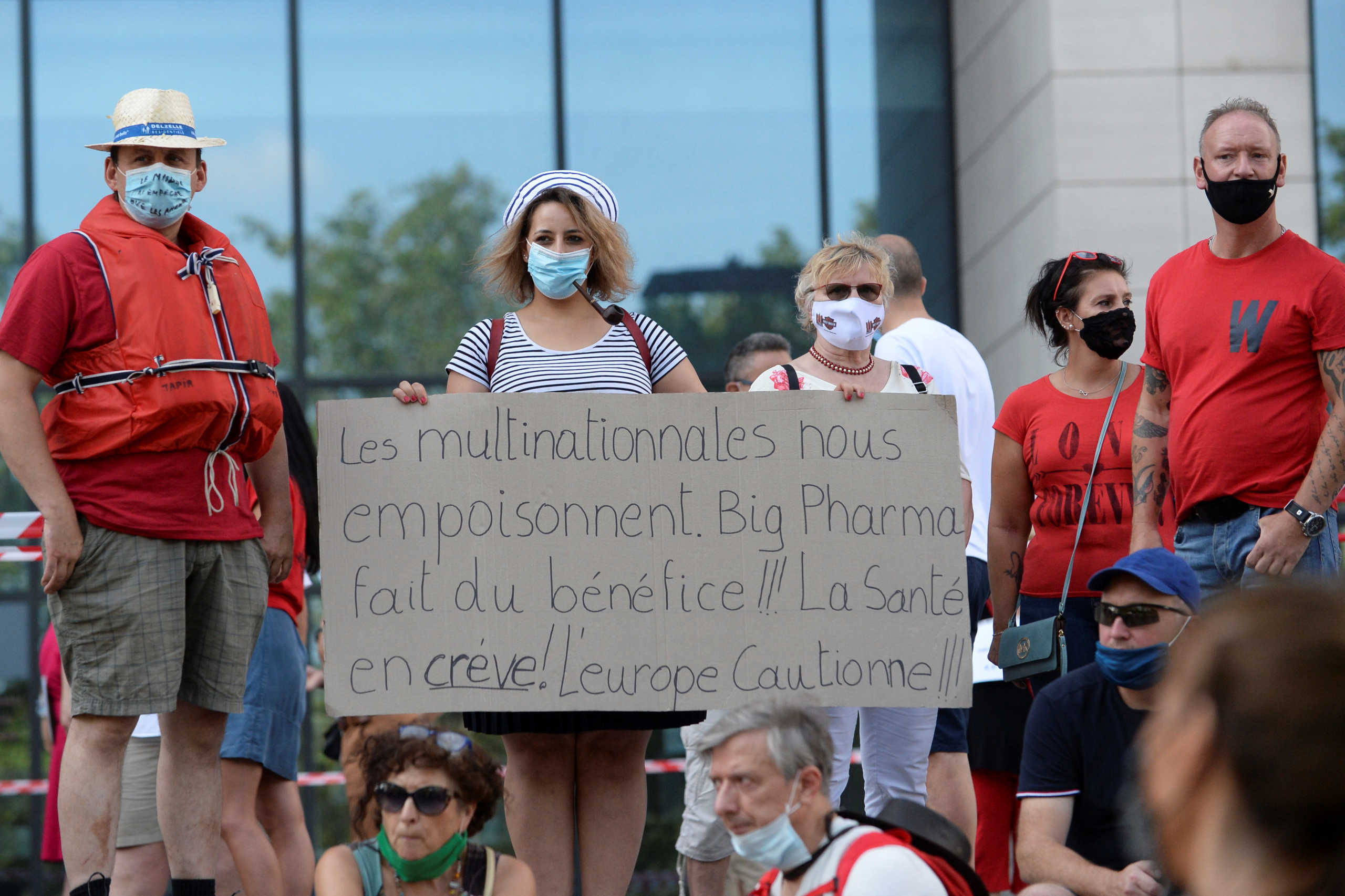 Demonstrators holding a sign reading "Multinational corporations poison us. Big Pharma makes profit. Health is dying." protest against the measures of the government to avoid the spread of the coronavirus disease (COVID-19), amid its outbreak, near to the Finance Tower in Brussels, Belgium, August 16, 2020. REUTERS