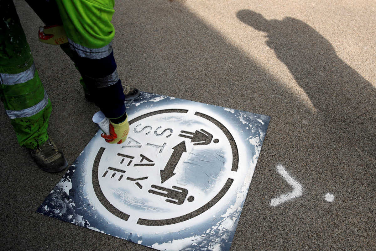 FILE PHOTO: A council worker sprays a social distancing marker on the ground in Oldham amid the coronavirus disease (COVID-19) outbreak, Britain July 29, 2020. REUTERS