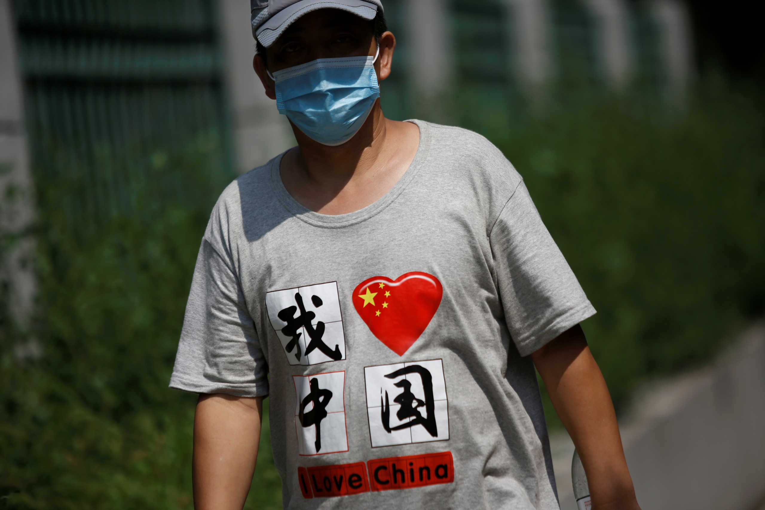 A man wearing a face mask and a shirt with   Chinese characters reading "I love China" walks on a street, after Beijing Centre for Disease Prevention and Control announced that wearing face masks are no longer mandatory outdoor in Beijing, following the coronavirus disease (COVID-19) outbreak, China August 21, 2020. REUTERS