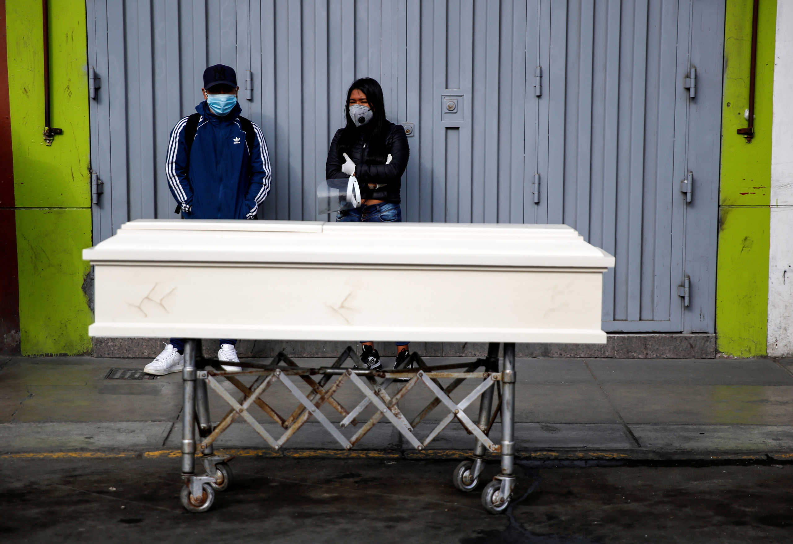 People stand next to a coffin holding the body of a family member who died after police raided a nightclub for hosting a party in violation of the coronavirus disease (COVID-19) restrictions, in Lima, Peru August 24, 2020. REUTERS