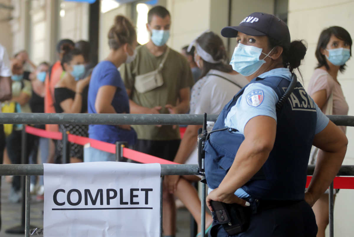 A French municipal police employee stands near a fence with a sign reading "full" as people wait in line at a testing site for coronavirus disease (COVID-19) in Nice, France, August 24, 2020.   REUTERS