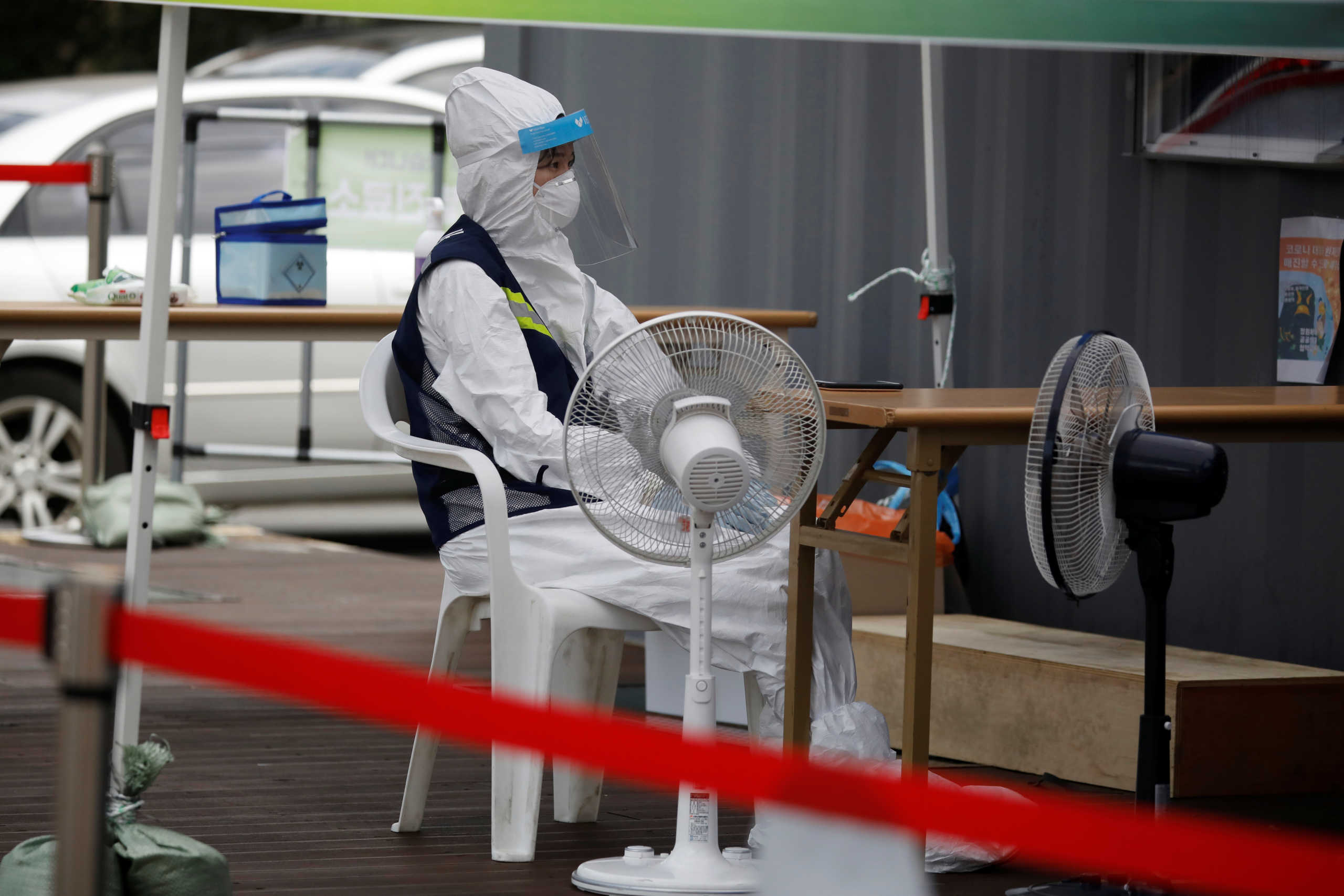 A nurse wearing personal protective equipment uses fans to cool down at a makeshift clinic for the coronavirus disease (COVID-19) in Seoul, South Korea, August 26, 2020.   REUTERS