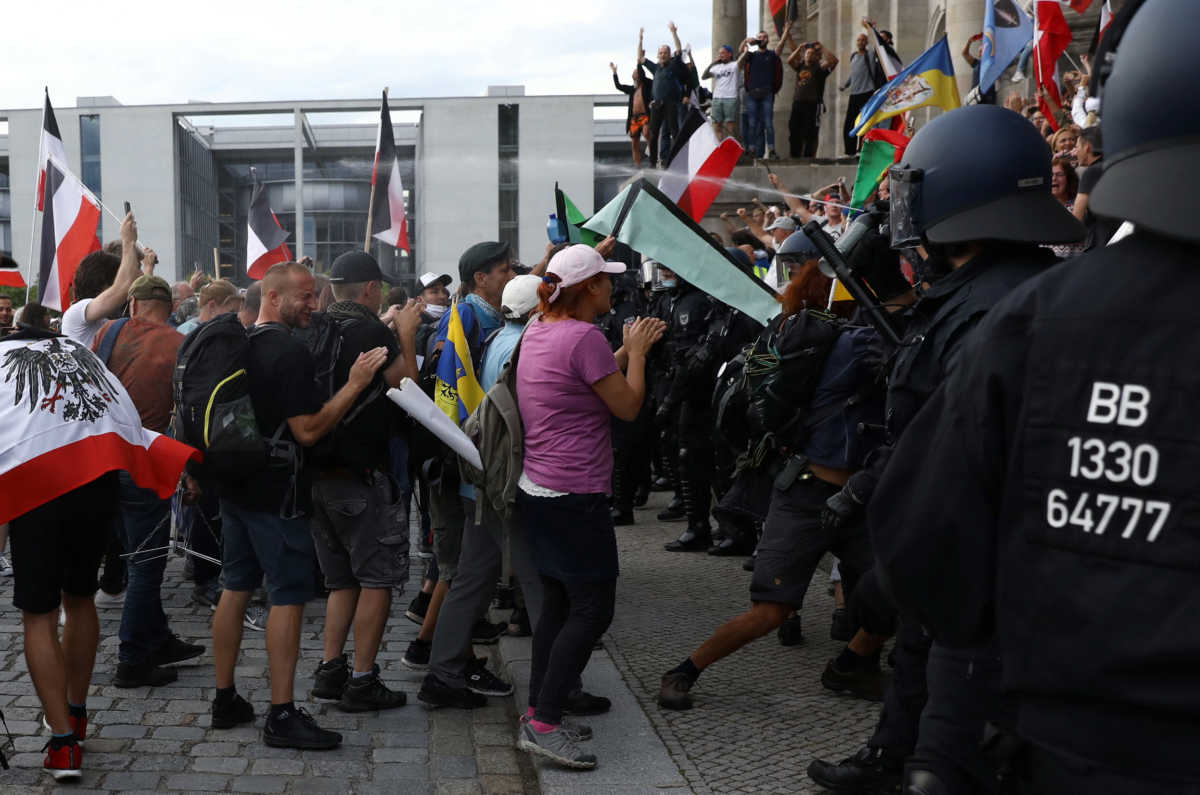 A police officer uses a pepper spray on protesters in front of the Reichstag Building during a rally against the government's restrictions following the coronavirus disease (COVID-19) outbreak, in Berlin, Germany, August 29, 2020. REUTERS