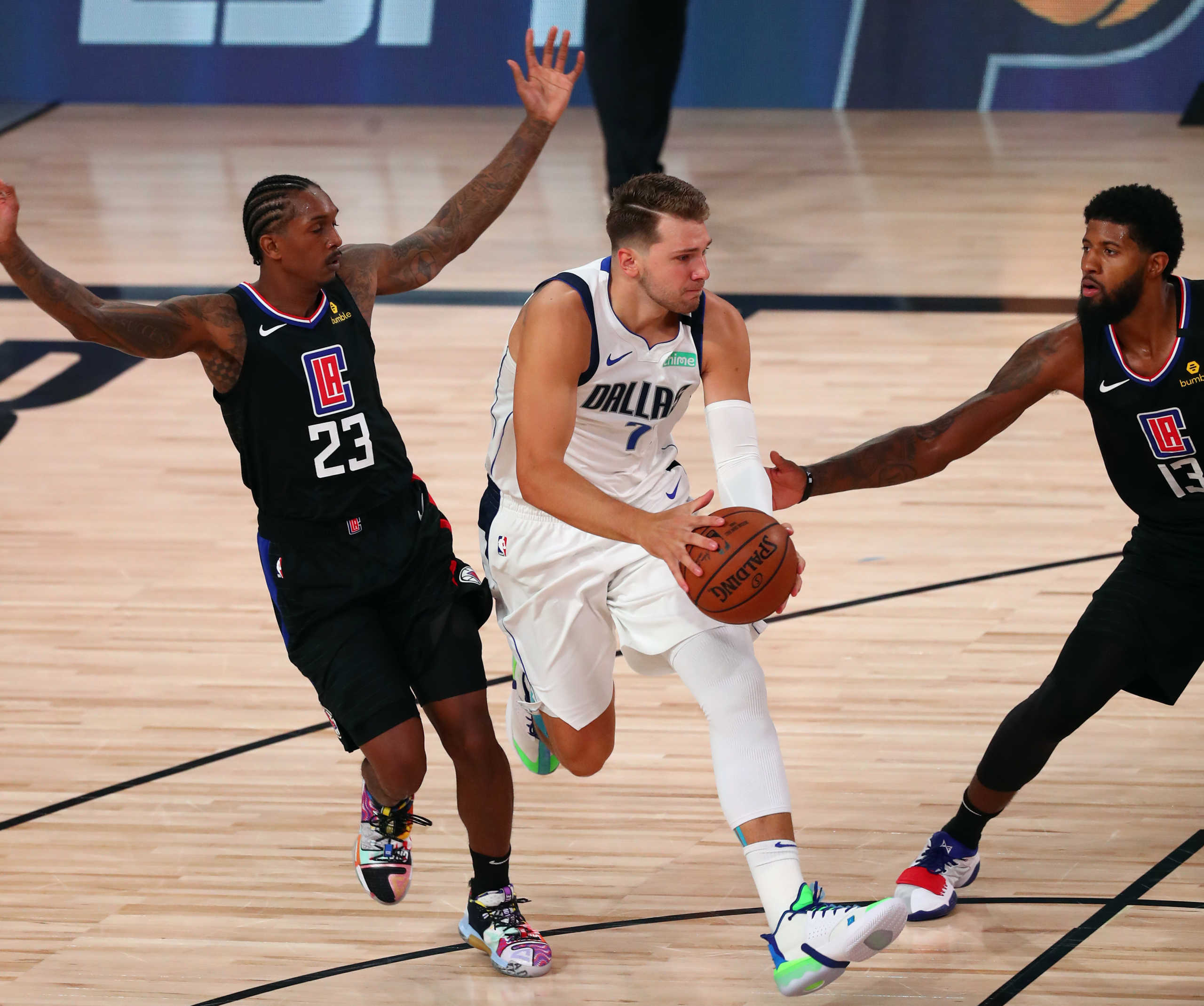 Aug 19, 2020; Lake Buena Vista, Florida, USA; Dallas Mavericks guard Luka Doncic (77) drives between LA Clippers guard Lou Williams (23) and guard Paul George (13) during the second half in game two of the first round of the 2020 NBA Playoffs at AdventHealth Arena. Mandatory Credit: Kim Klement-USA TODAY Sports
