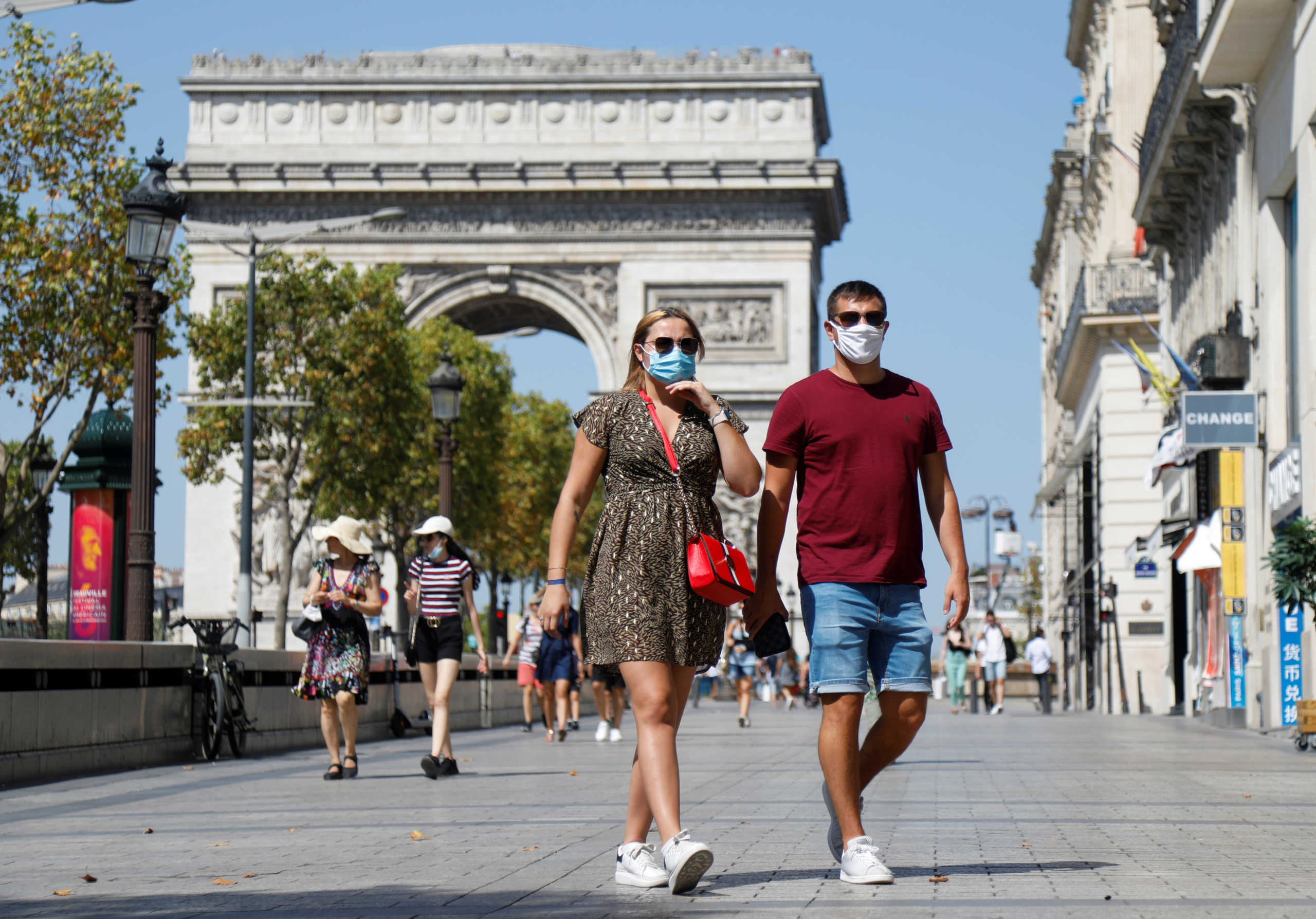 People wearing protective masks walk on the Champs-Elysees near the Arc de Triomphe, as France reinforces mask-wearing as part of efforts to curb a resurgence of the coronavirus disease (COVID-19) across the country, in Paris, France August 12, 2020. REUTERS