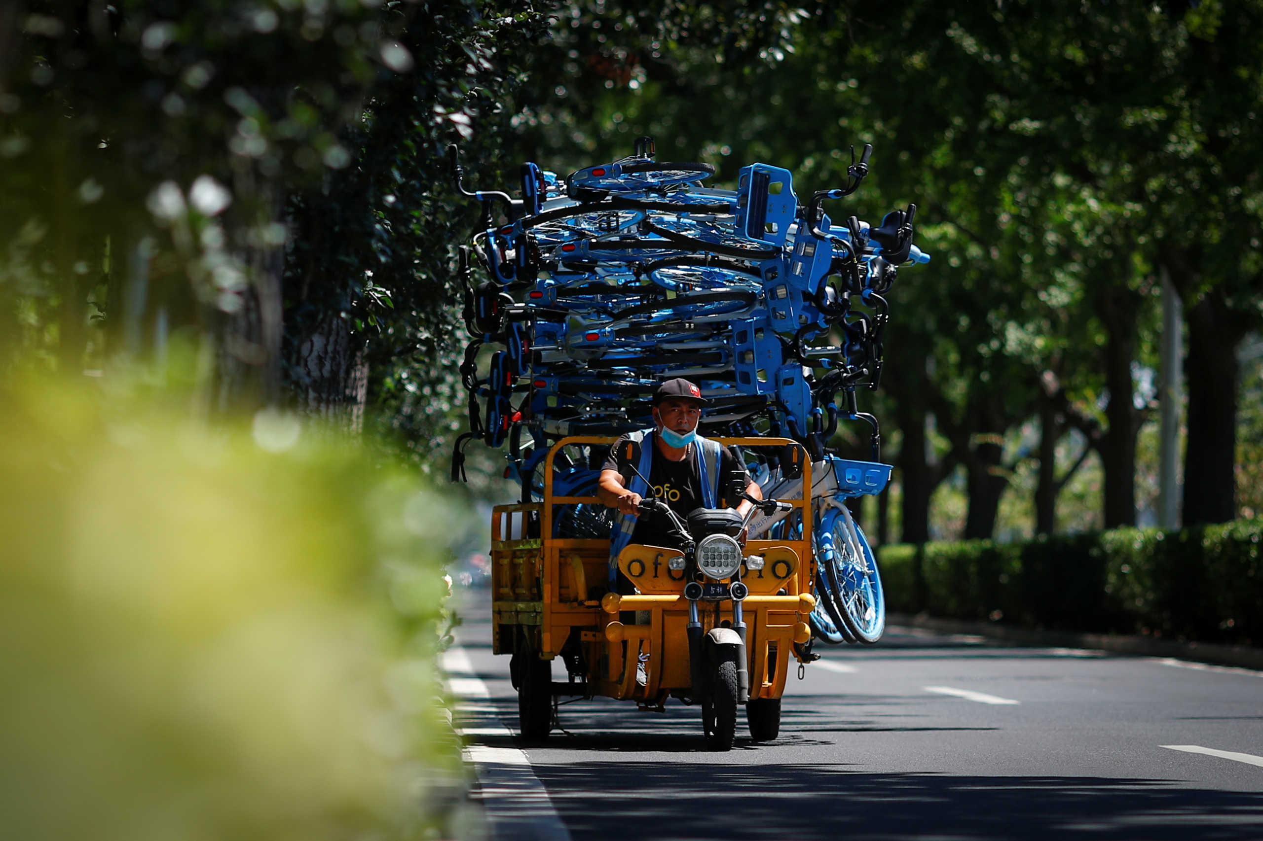 A worker transports Hellobike shared bicycles on an electric tricycle following an outbreak of the coronavirus disease (COVID-19) in Beijing, China, August 4, 2020. Picture taken August 4, 2020.  REUTERS