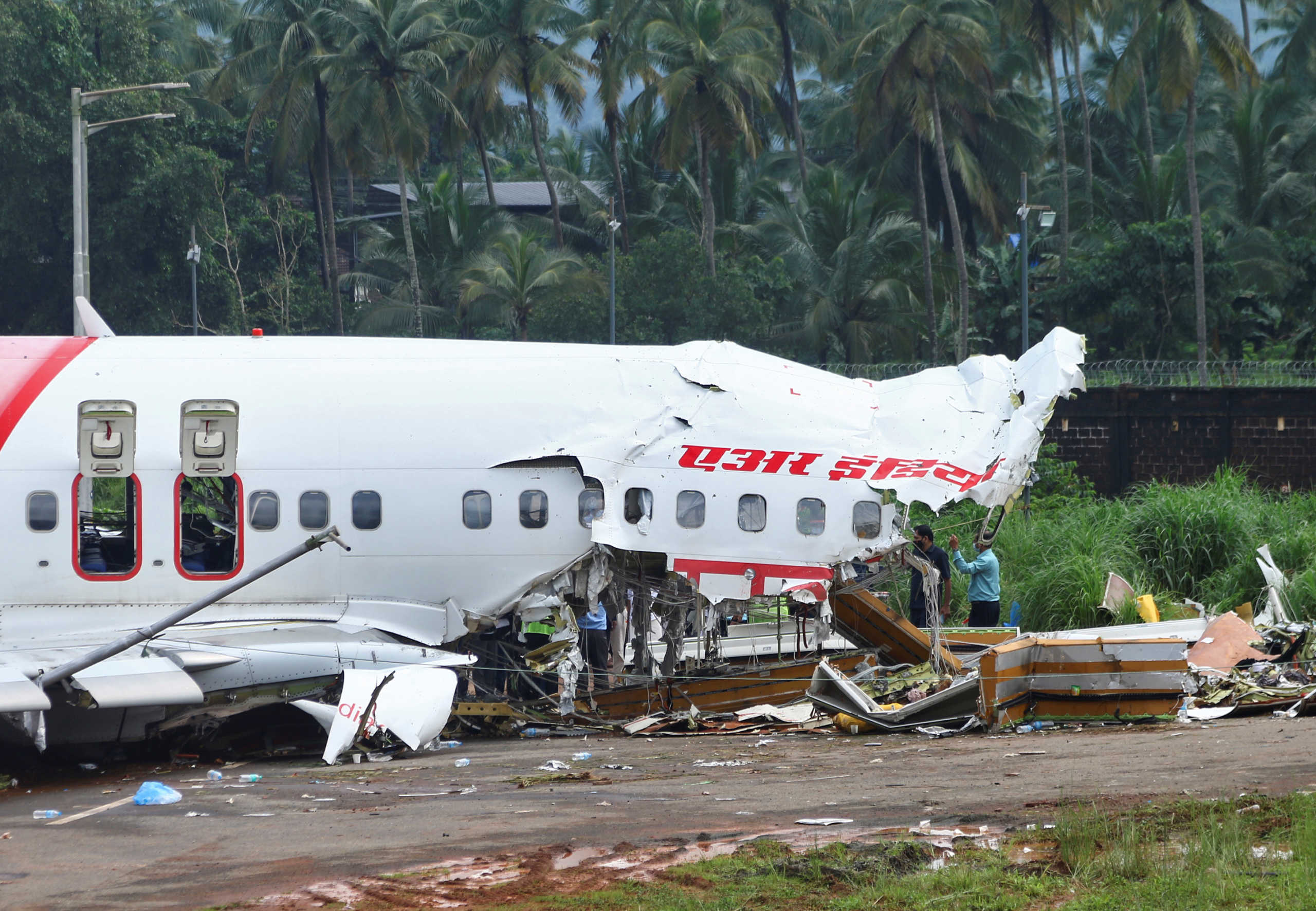 Officials inspect the site where a passenger plane crashed when it overshot the runway at the Calicut International Airport in Karipur, in the southern state of Kerala, India, August 8, 2020. REUTERS