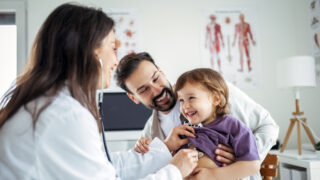 Paediatrician Examining Child with Stethoscope While Father Watches