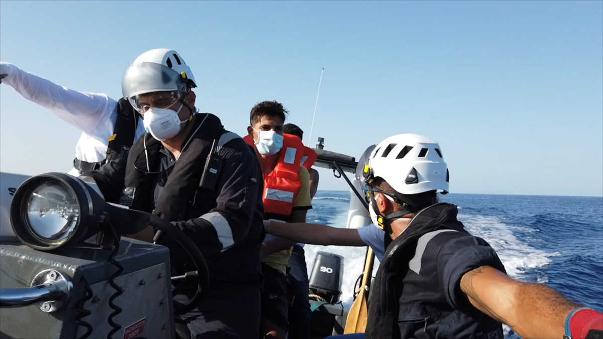 A member of the rescue team speaks with a migrant on a rubber dinghy, at sea off the coast of Libya, August 22, 2020, in this still image taken from the video. Sea-Watch