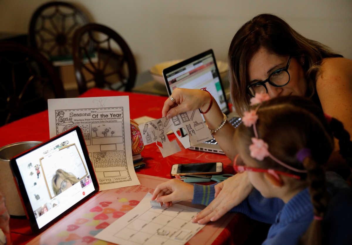 Isabel Martin del Campo, helps her daughter Ines, 6, on her English class, taught by the child's private school, as millions of students returned to classes virtually on Monday after schools were ordered into lockdown in March, due to the coronavirus disease (COVID-19) outbreak, in Mexico City, Mexico August 24, 2020. REUTERS