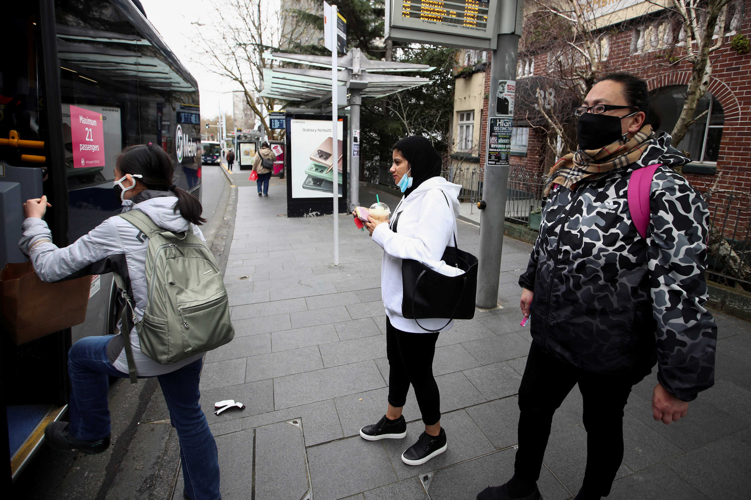 People wearing face masks prepare to board a bus on the first day of New Zealand's new coronavirus disease (COVID-19) safety measure that mandates wearing of a mask on public transport, in Auckland, New Zealand, August 31, 2020.  REUTERS