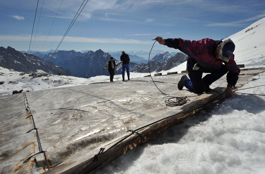 epa02725570 A worker covers the Schneeferner glacier to protect it from sun on the 2962 meters high Zugspitze nearby Garmisch-Partenkirchen, Germany, 10 May 2011. Germany's only glacier will be covered with foil and tarpaulin over the summer.  EPA