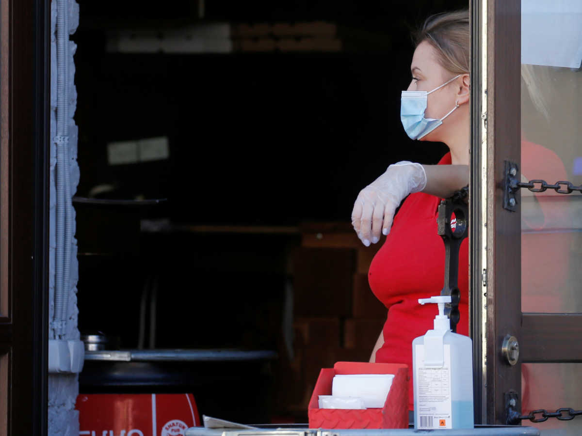 A waitress wearing a protective face mask and gloves amid the outbreak of the coronavirus disease (COVID-19) waits for clients in a cafe in Kyiv, Ukraine August 6, 2020. REUTERS