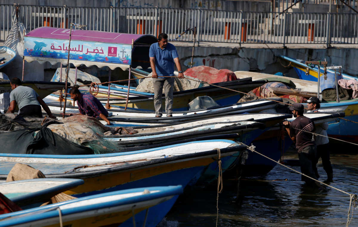 Fishermen push a boat at the seaport of Gaza City, after Israel reduced the area where it permits Gazans to fish in response to Palestinians launching incendiary balloons towards Israel, August 16, 2020. REUTERS