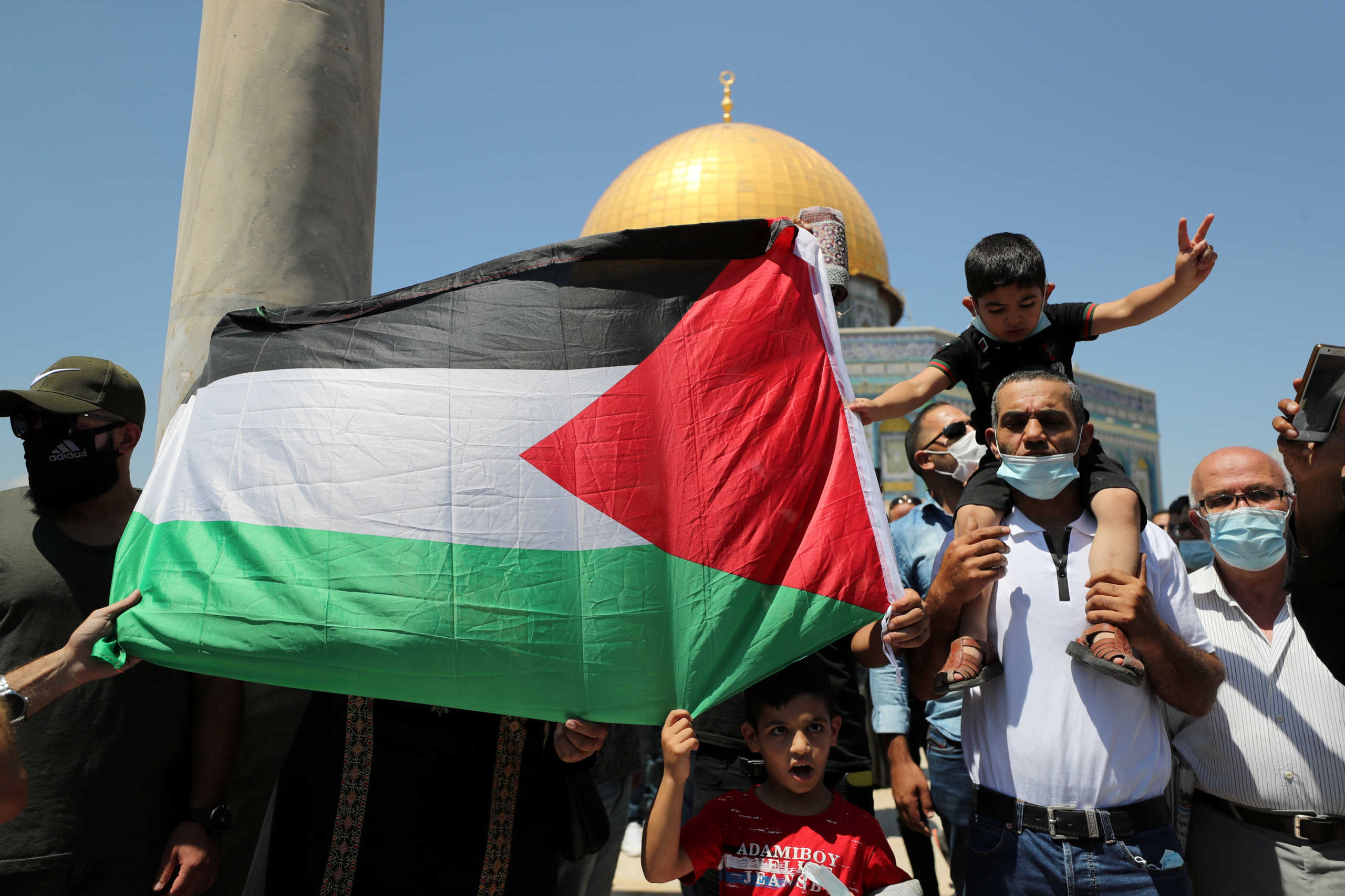 People hold a Palestinian flag during a protest against the United Arab Emirates, in Jerusalem's Old City, August 14, 2020. REUTERS