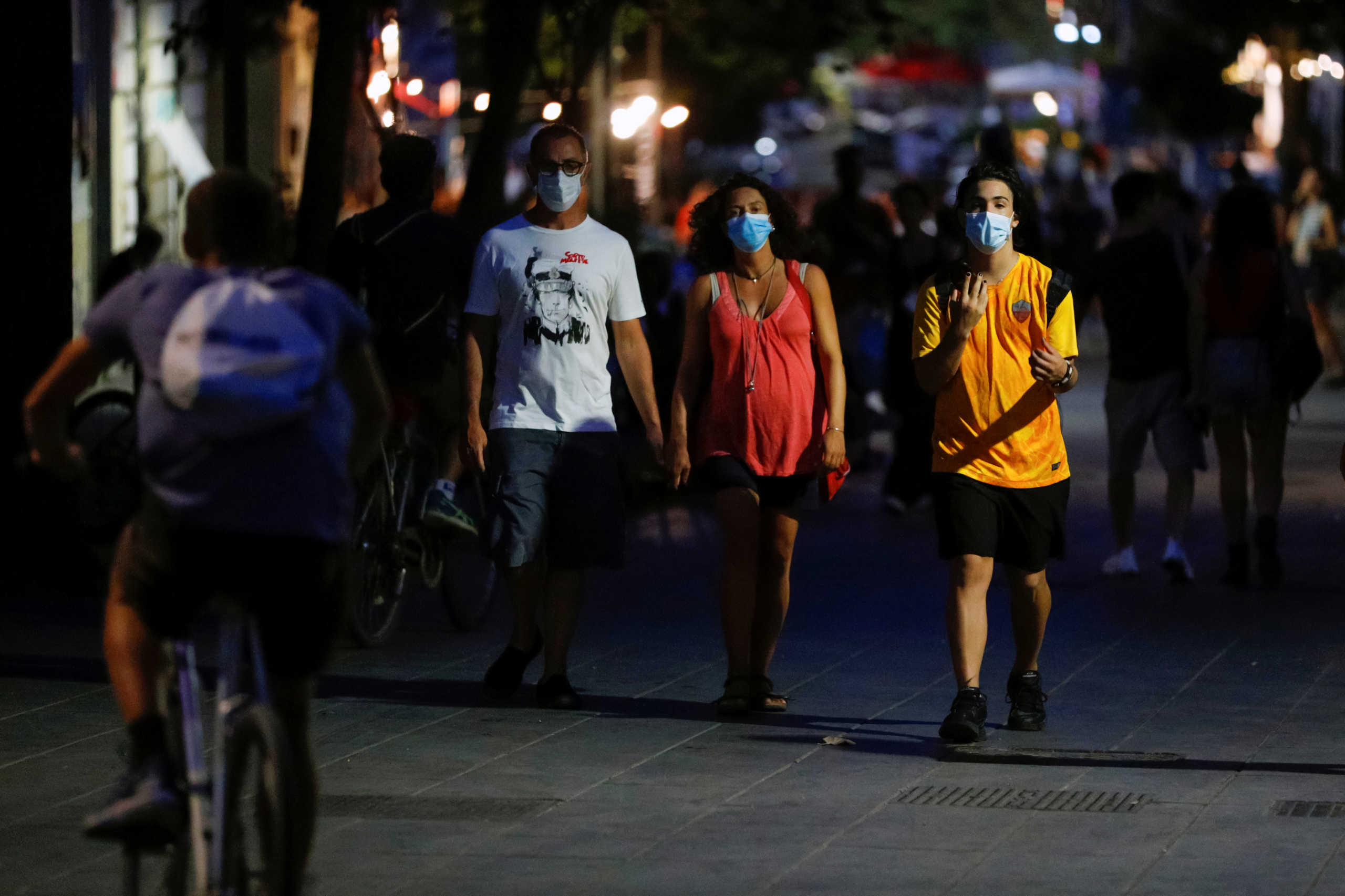 People wear masks as they walk on a street following a government decree that states face coverings must be worn between 6 p.m. and 6 a.m. near bars and pubs and in areas where gatherings are more likely, due to the coronavirus disease (COVID-19) outbreak, in Rome, Italy August 17, 2020. Picture taken August 17, 2020. REUTERS