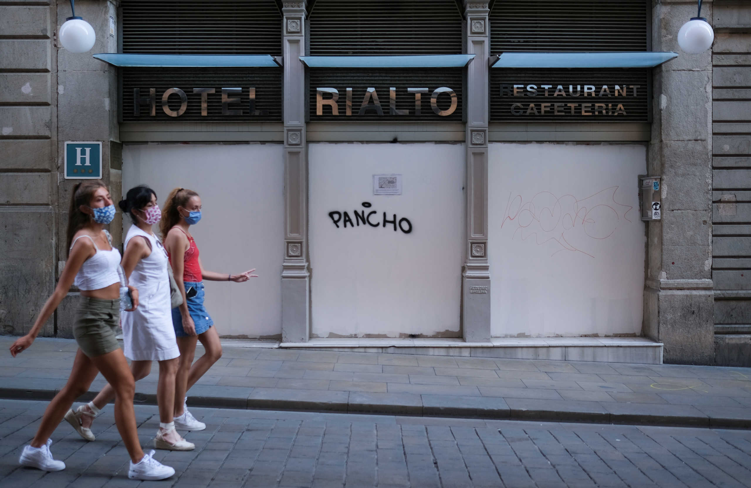 Women wearing face masks walk past a closed hotel at Barrio Gotico (Gothic Quarter), after Catalonia's regional authorities announced restrictions to contain the spread of the coronavirus disease (COVID-19) in Barcelona, Spain August 7, 2020. Picture taken August 7, 2020. REUTERS