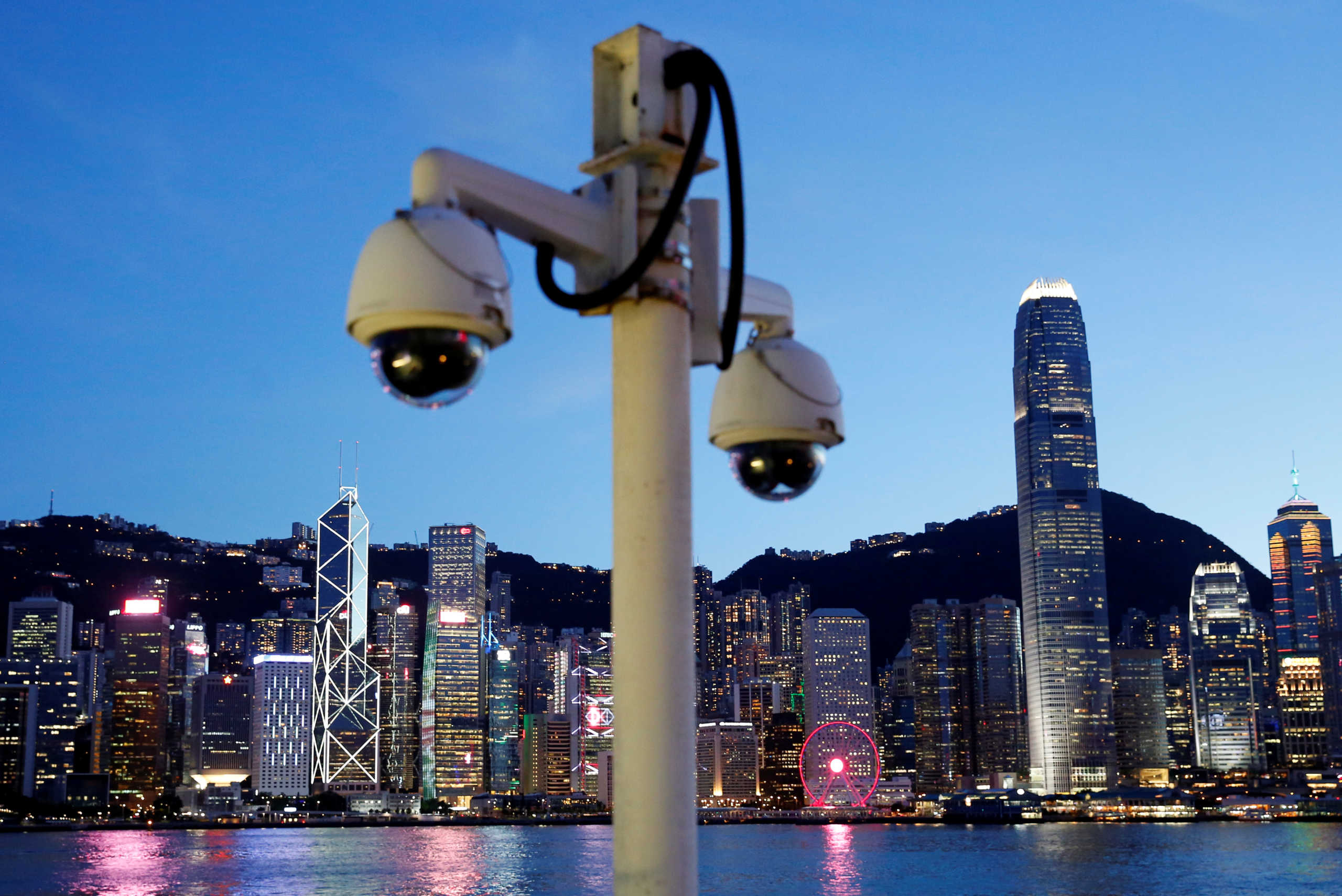 A pair of surveillance cameras are seen along the Tsim Sha Tsui waterfront as skyline buildings stand across Victoria Harbor in Hong Kong, China July 28, 2020. REUTERS
