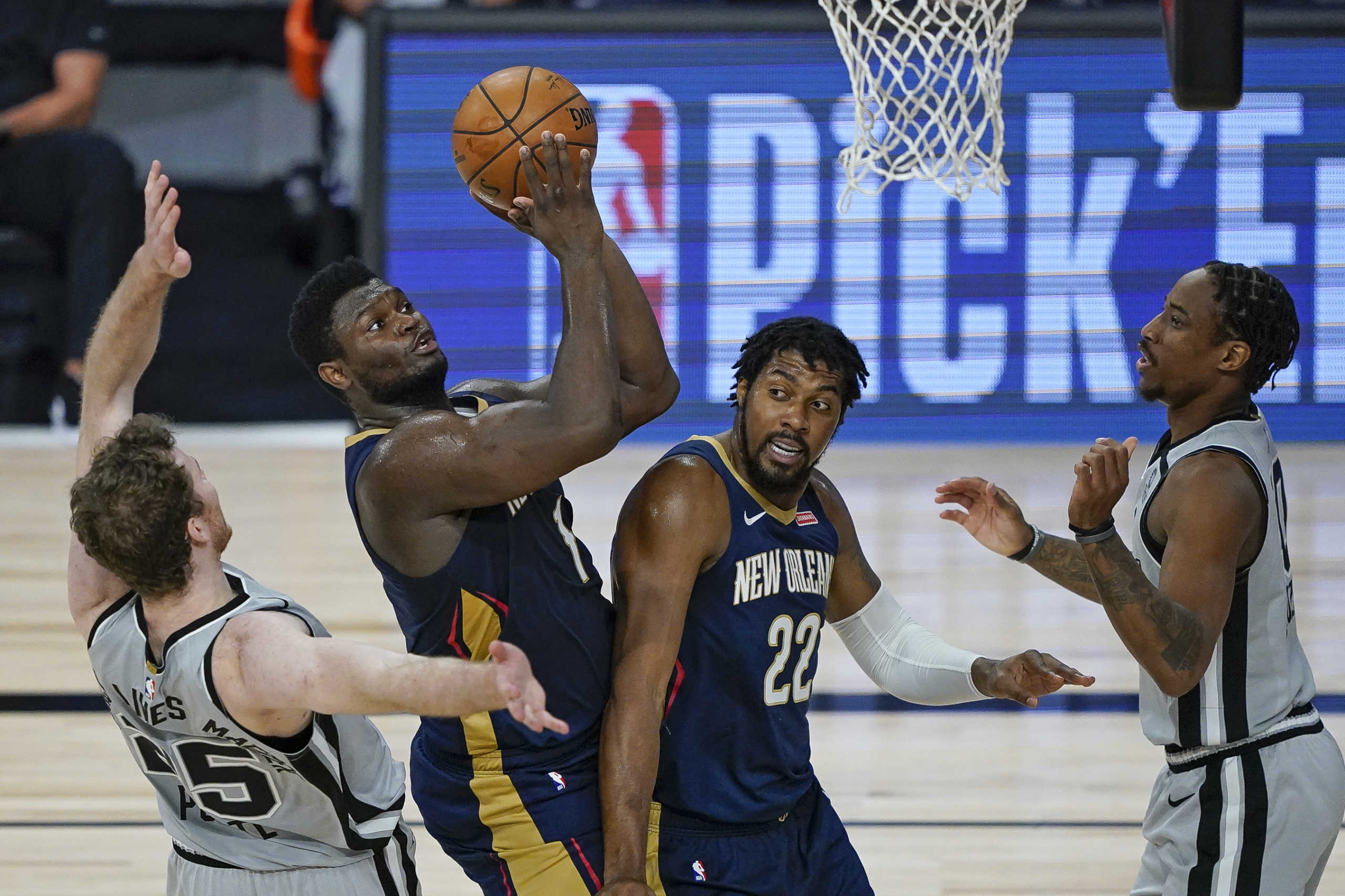 Aug 9, 2020; Lake Buena Vista, Florida, USA; New Orleans Pelicans forward Zion Williamson (middle) with help from teammate Derrick Favors (22) takes a shot as he gets past San Antonio Spurs center Jakob Poeltl (left) during the second half of an NBA basketball game at The Field House. Mandatory Credit: Ashley Landis